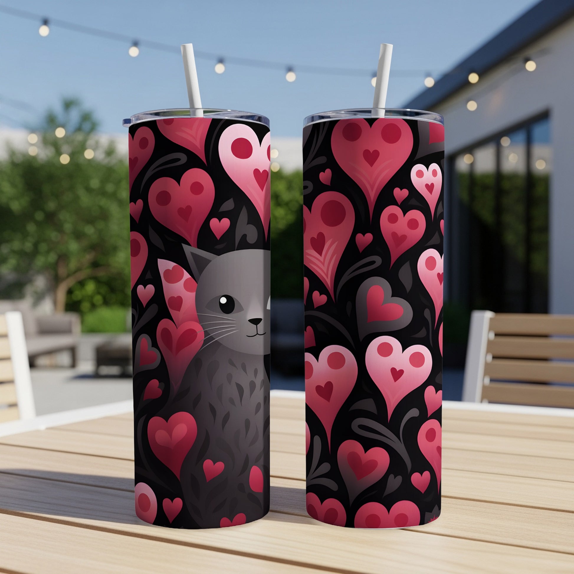 Two tumblers with a black background covered in pink and red hearts and a cat's face.