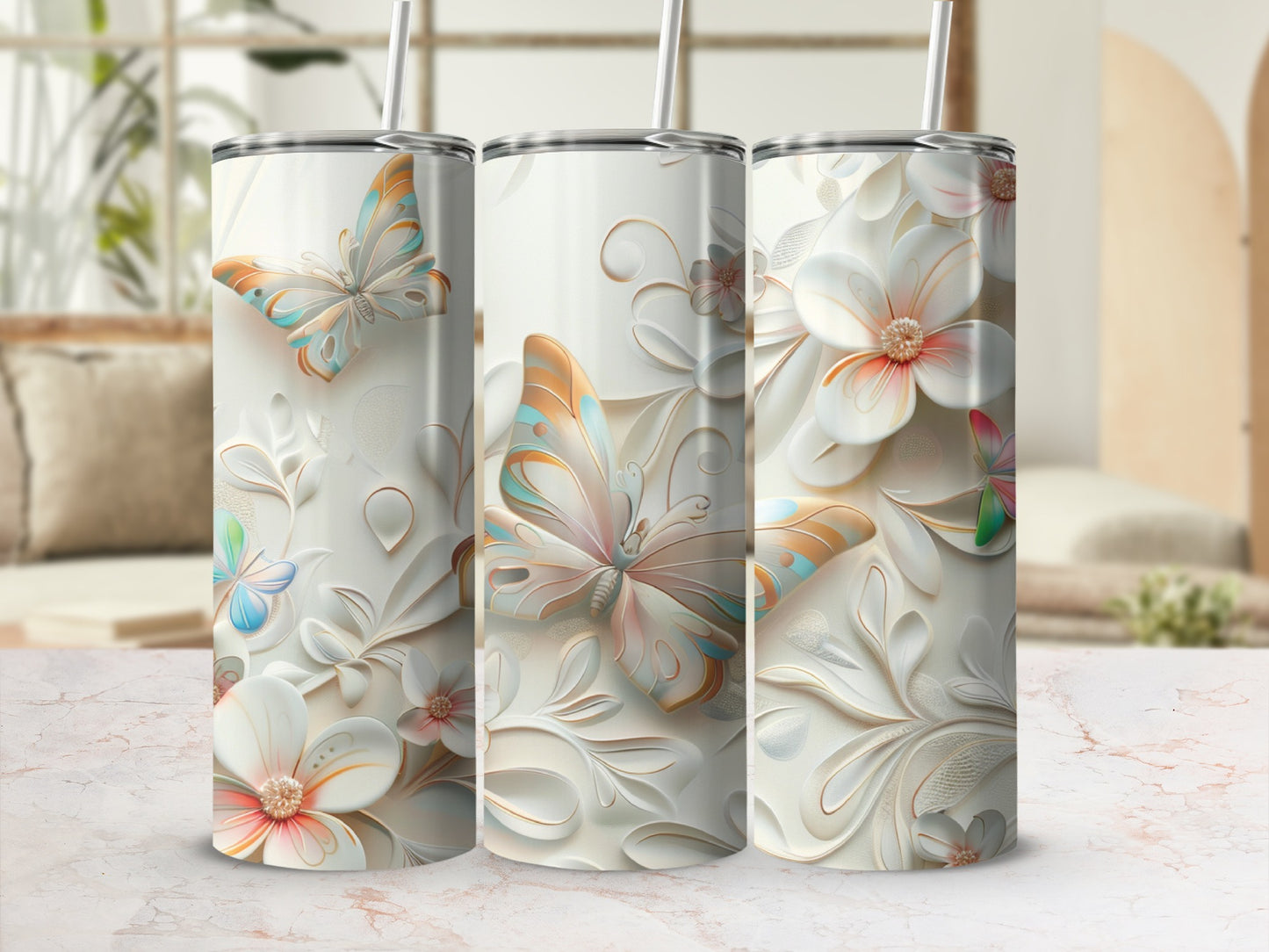 Three tumblers with butterflies and floral designs, on a marble surface.