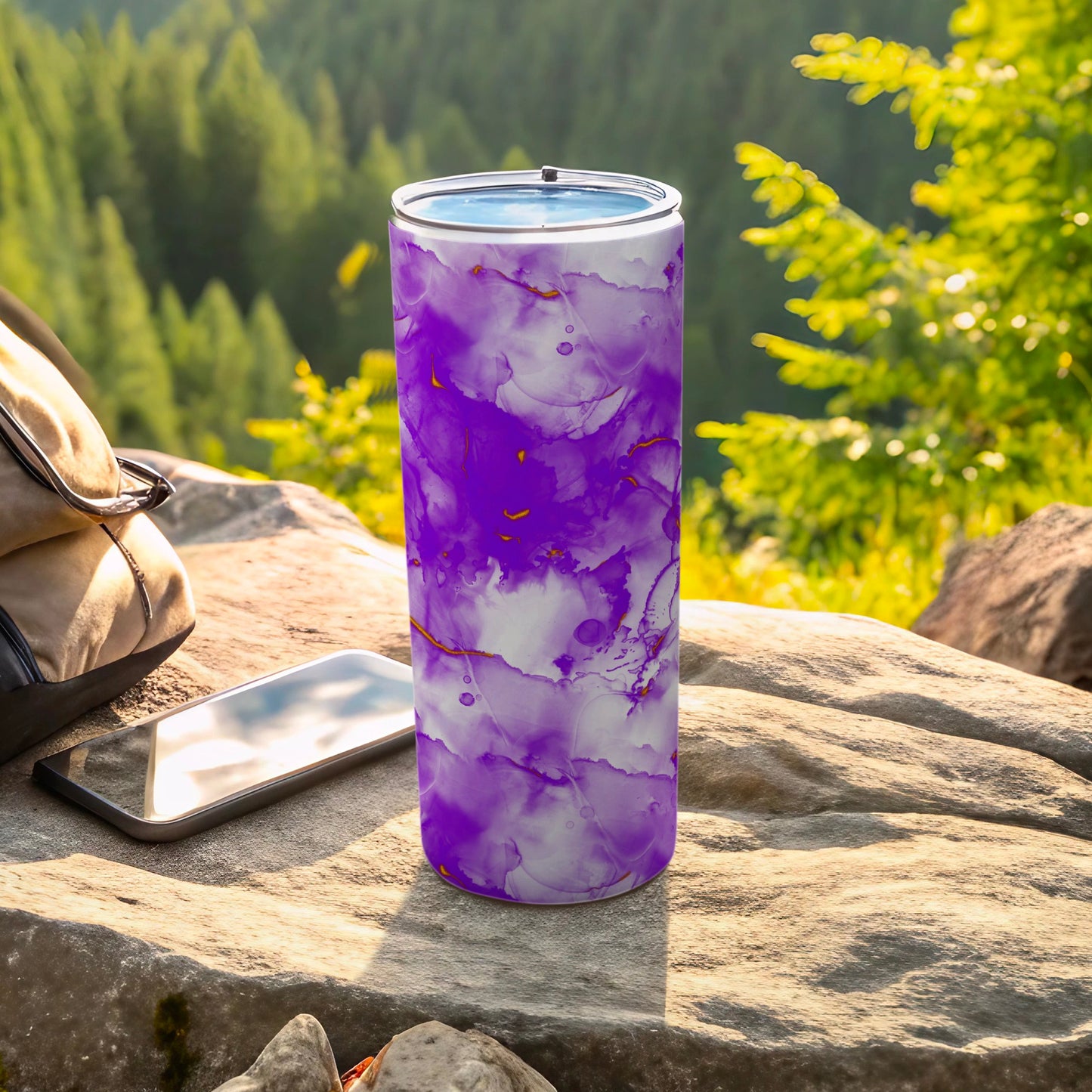 Purple abstract marbled tumbler with gold accents on a rock.