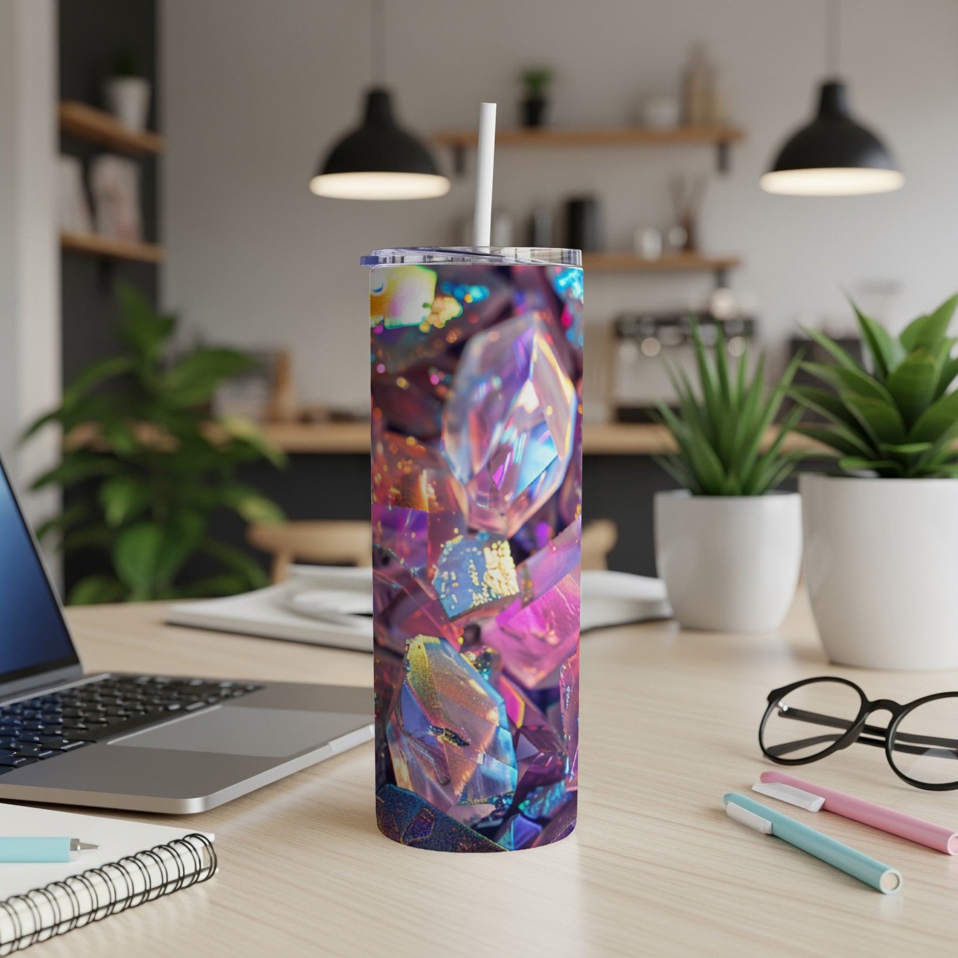 Tumbler with abstract gem pattern, white straw, laptop, and pens on desk.