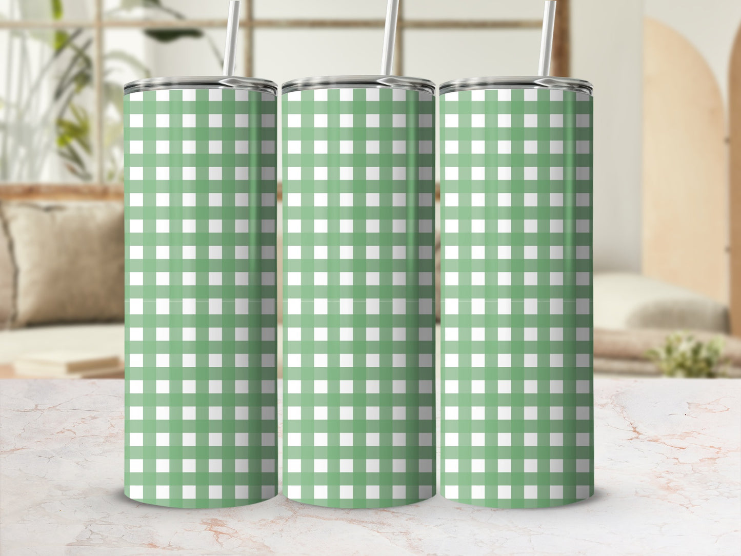 Three green and white plaid tumblers with straws on a marble surface.