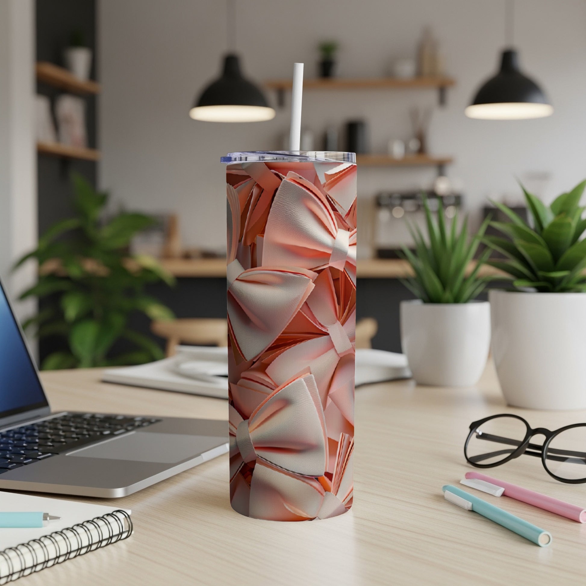 Pink ribbon pattern on a tumbler with a straw, on a desk.
