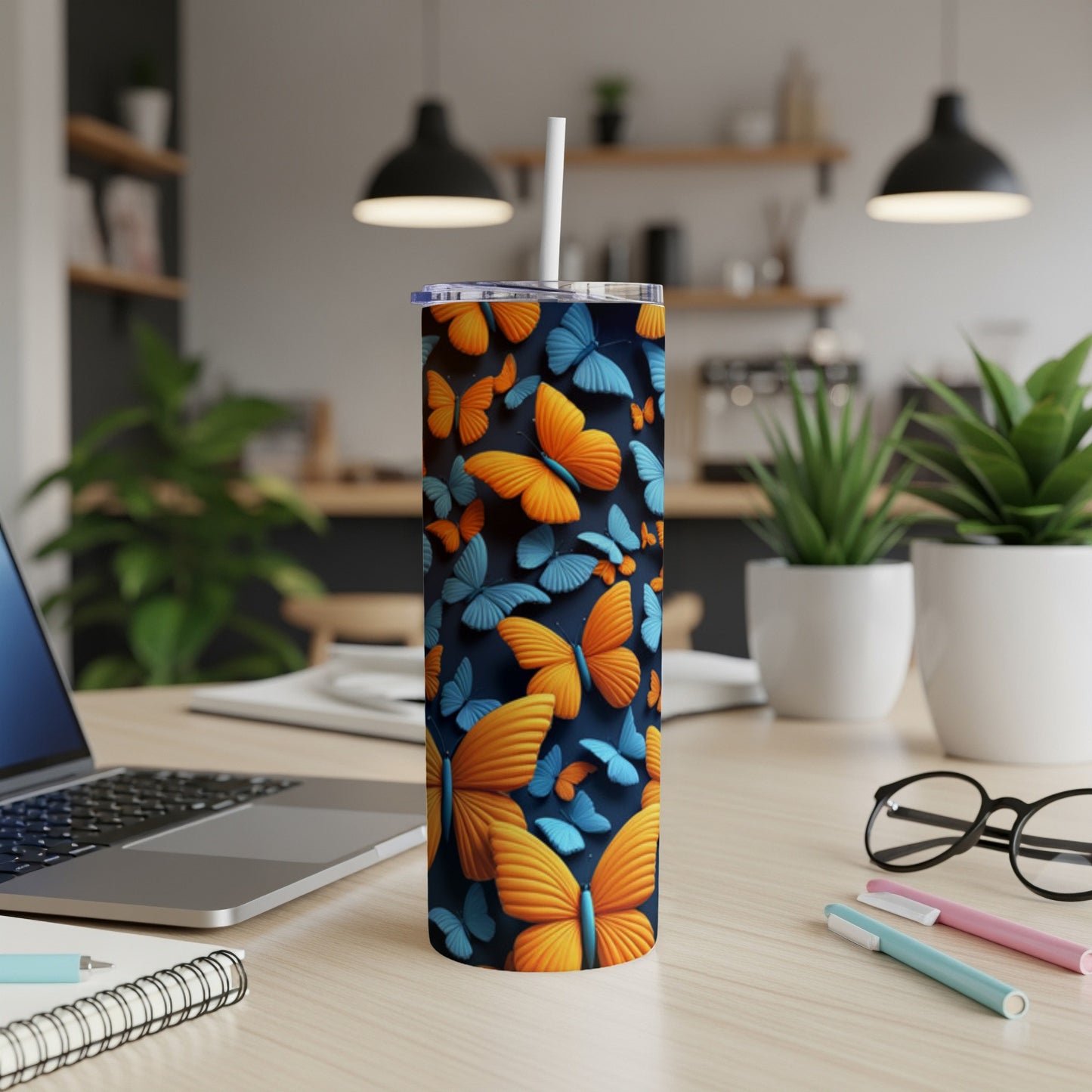 Blue and orange butterfly tumbler with straw on a desk.