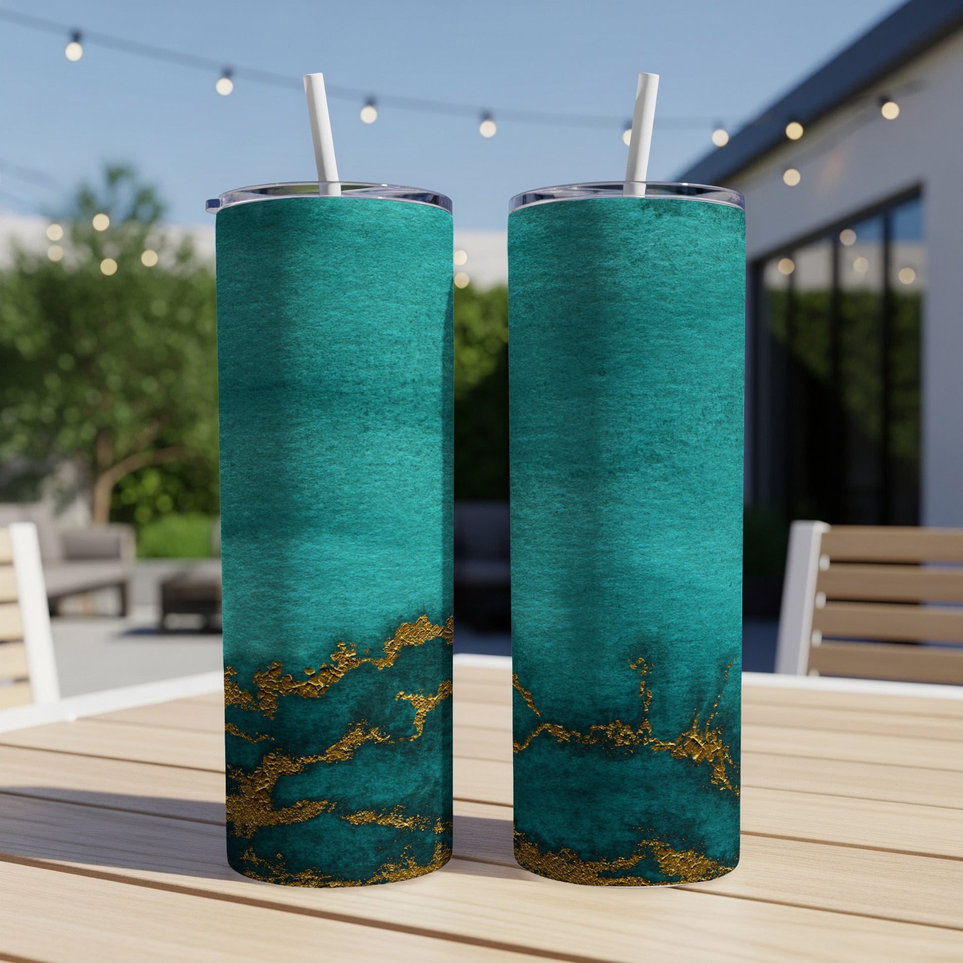 Two teal tumblers with gold marbling sit on a wooden table.