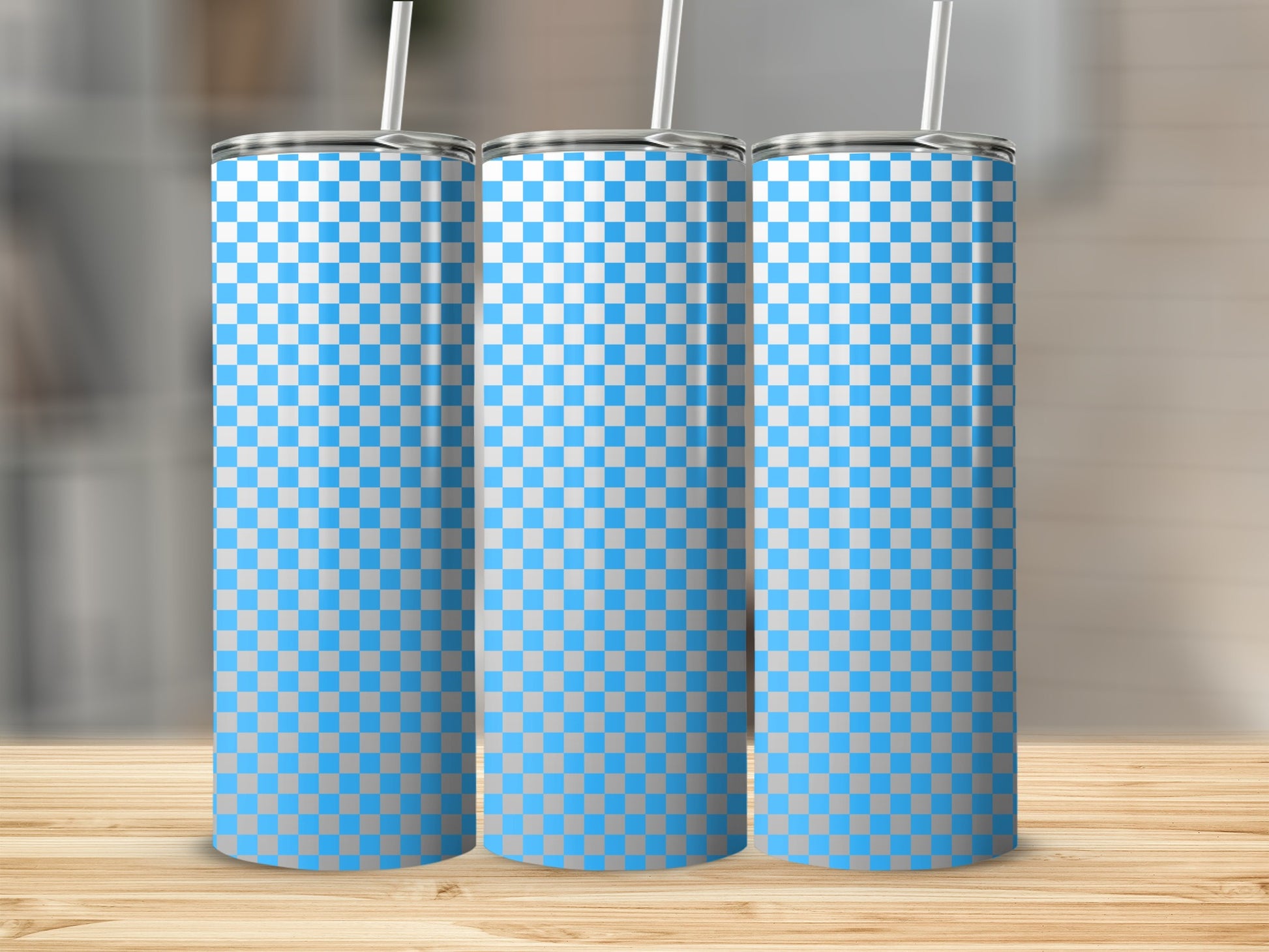 Three blue and white checkered tumblers with straws on a wooden surface.