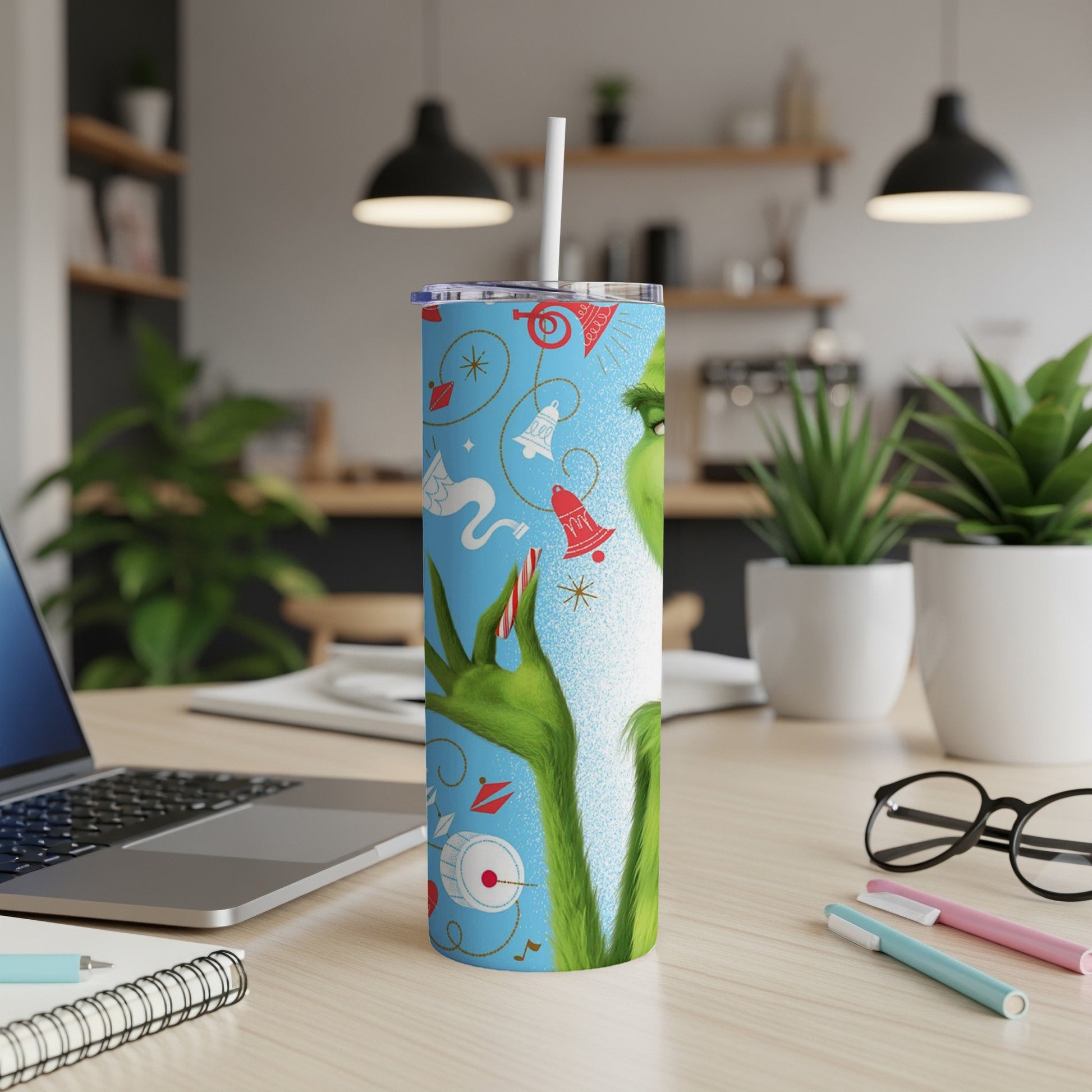 Grinch-themed tumbler with festive holiday icons on a desk.