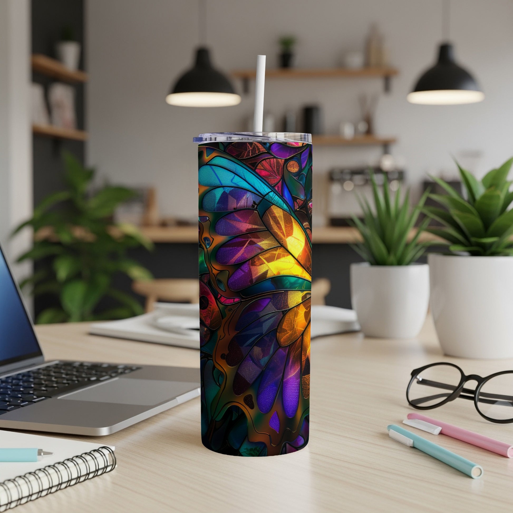 Colorful stained-glass butterfly pattern tumbler with straw on a desk.