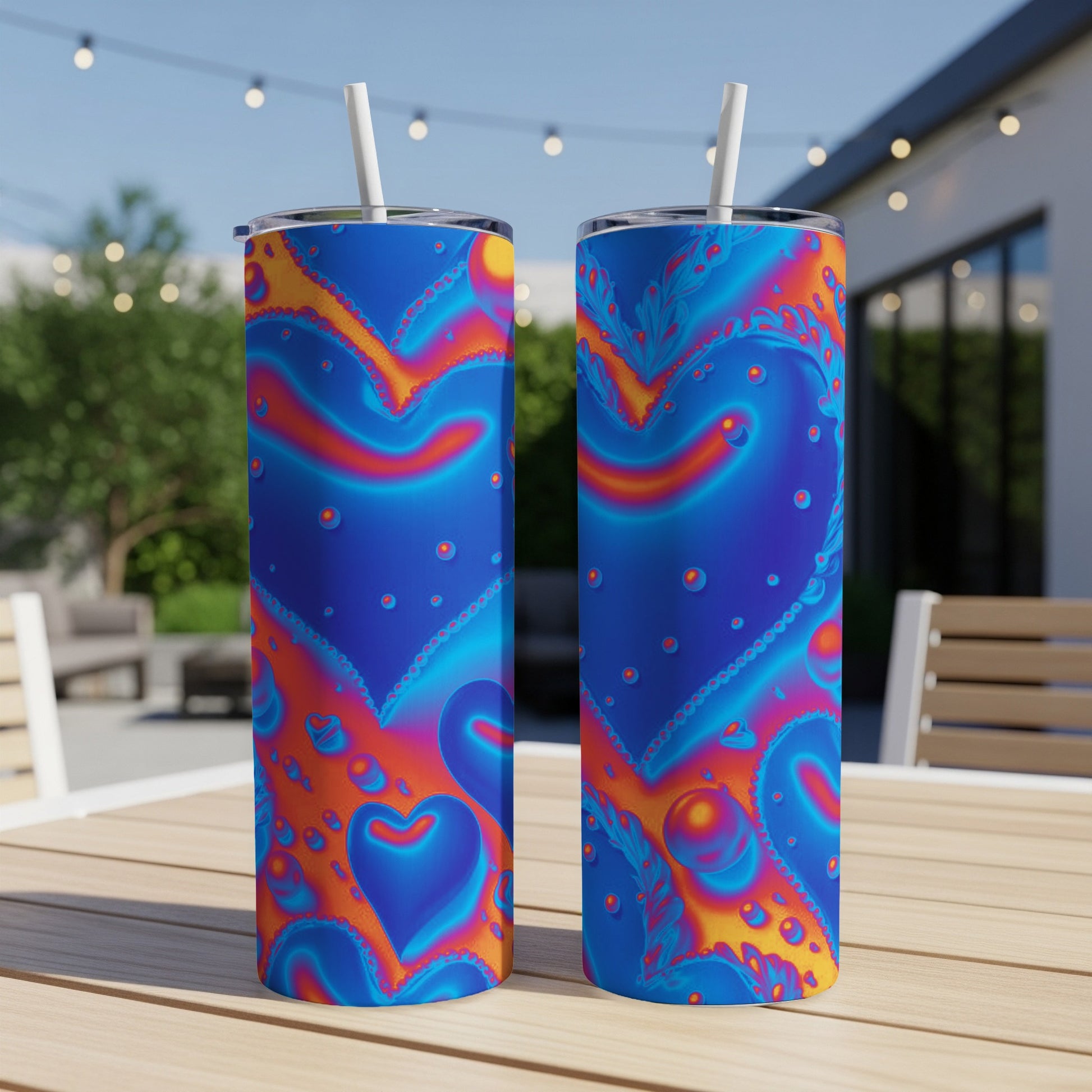 Two blue tumblers with vibrant heart and floral patterns and straws.