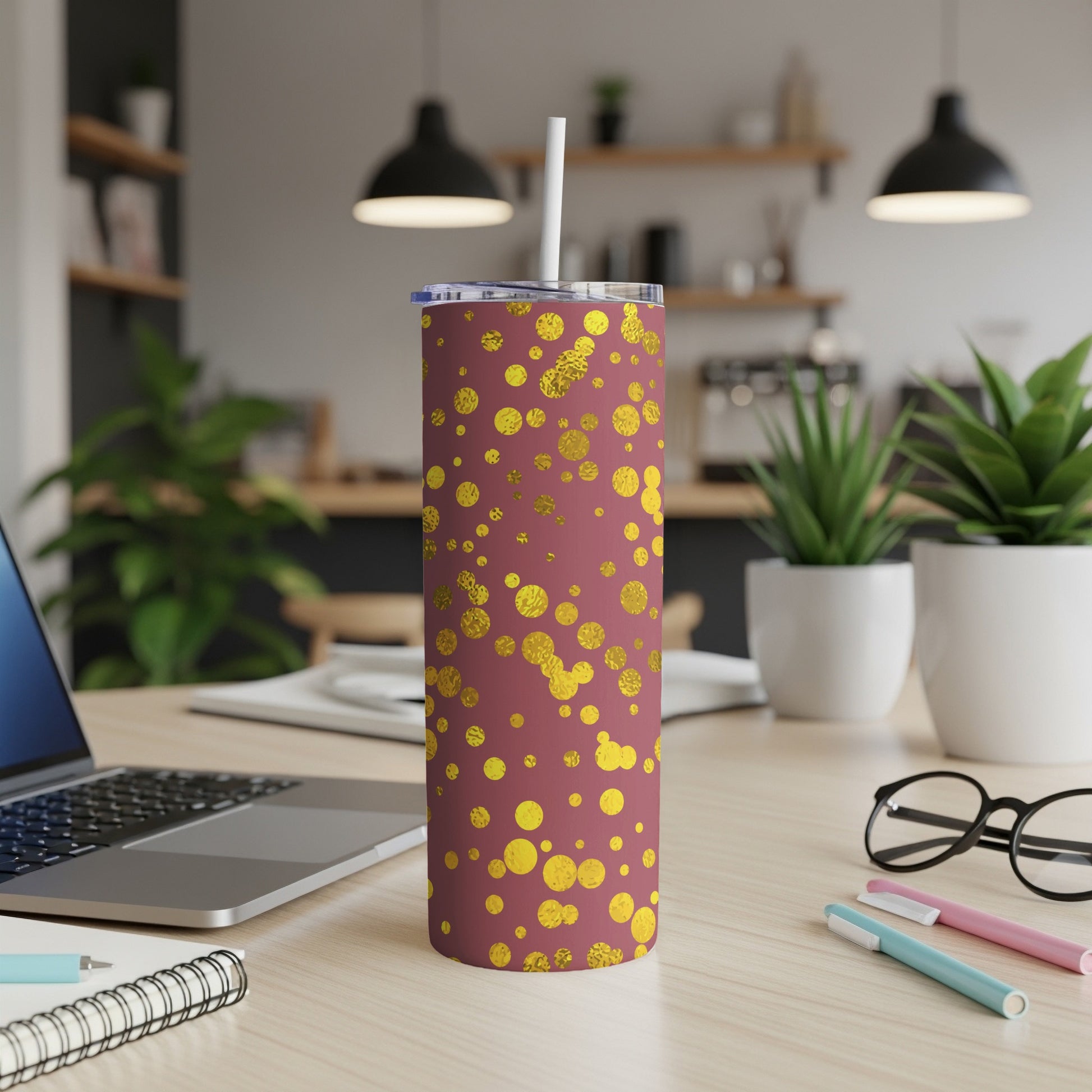 Maroon tumbler with gold polka dots and white straw on a desk.