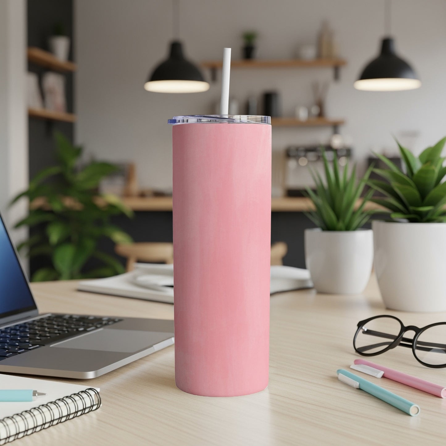 Pink insulated tumbler with straw on a desk with a laptop.