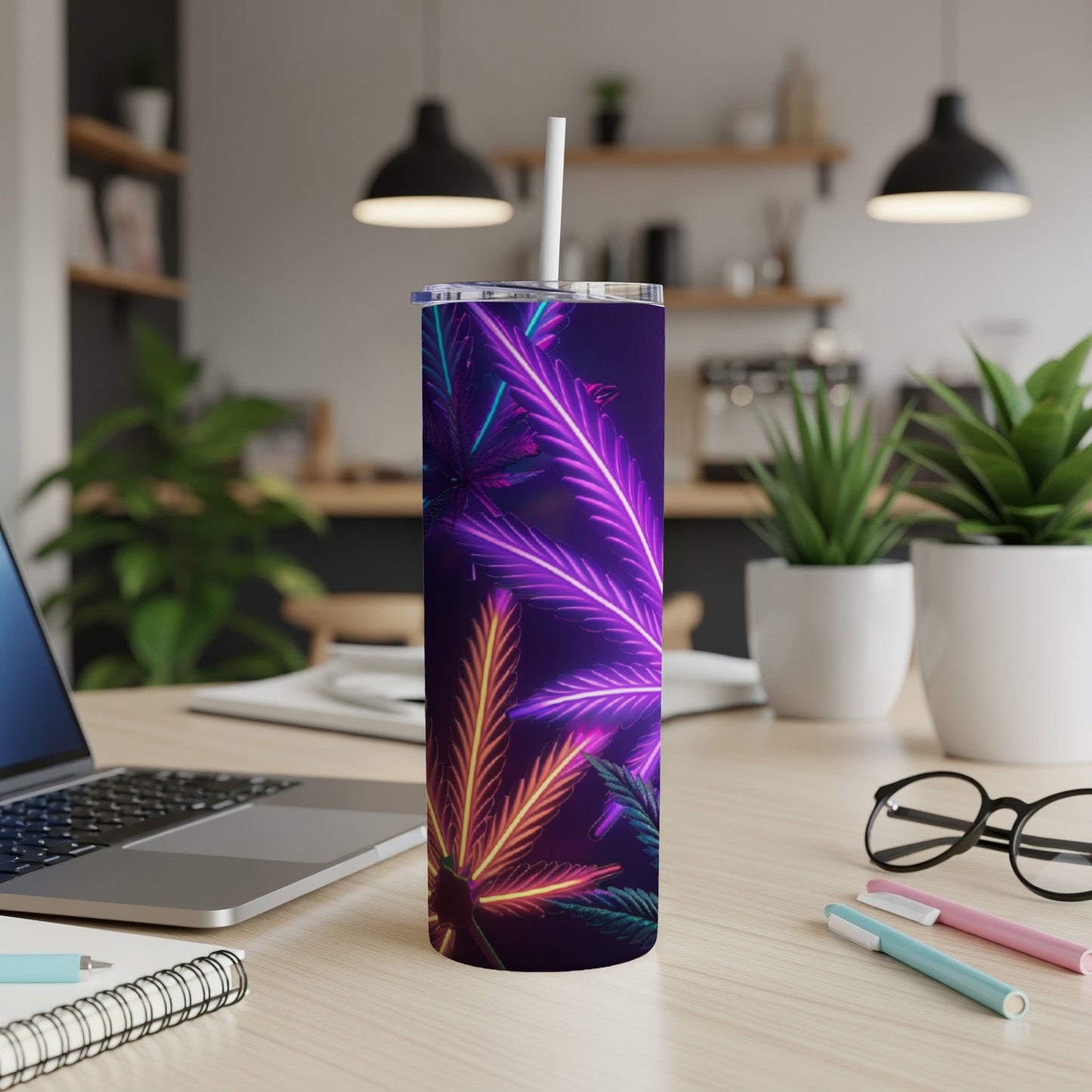 Purple tumbler with neon marijuana leaves design, on a desk.
