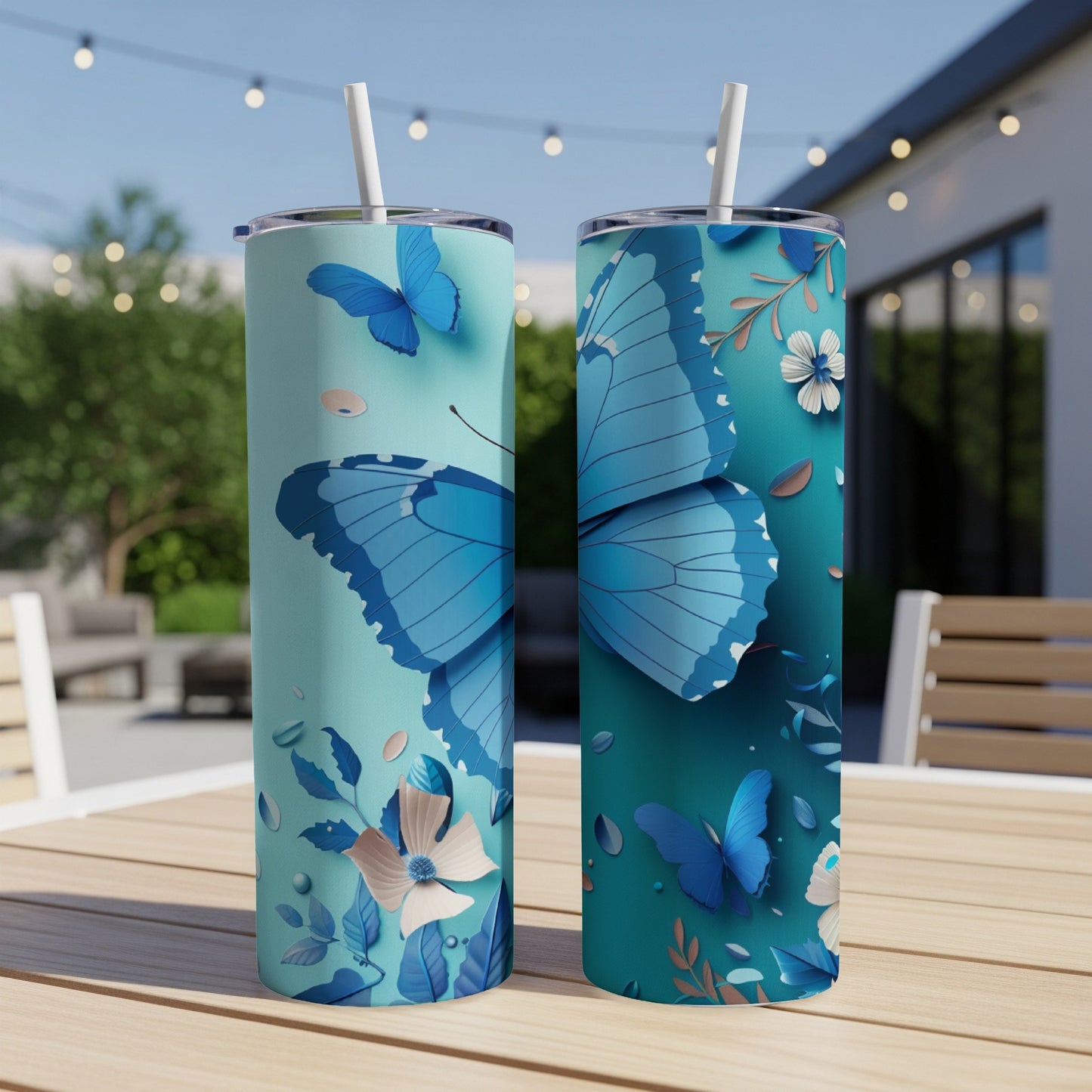 Two blue butterfly tumblers with floral accents on a wooden table outdoors.