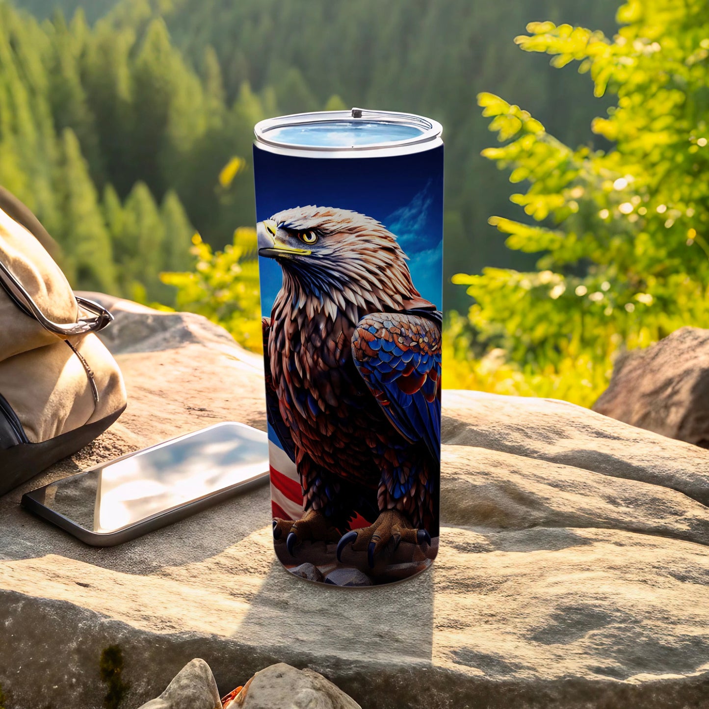 Tall tumbler with eagle and American flag design rests on rocks outdoors.