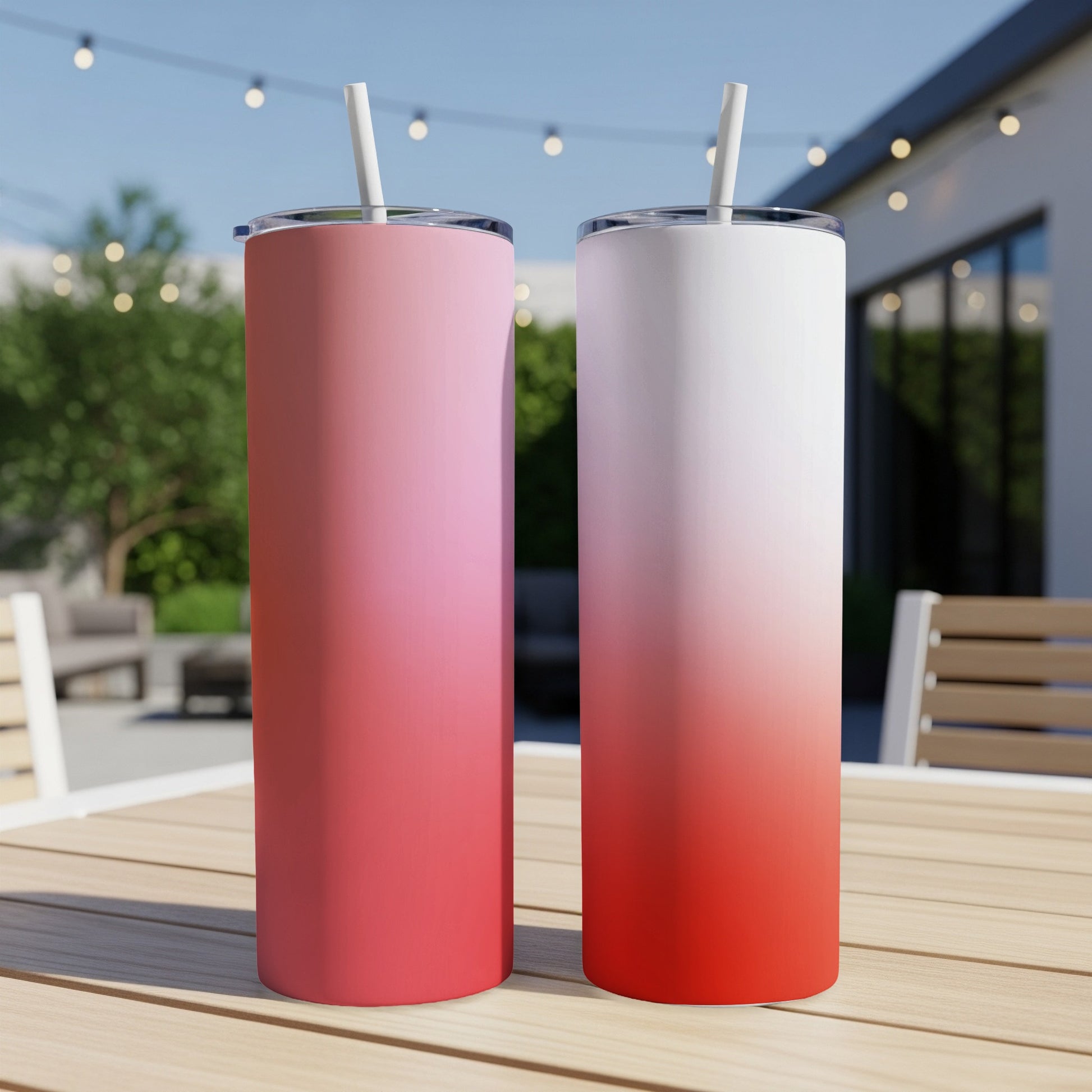 Two gradient pink and red tumblers with straws on a wooden table.
