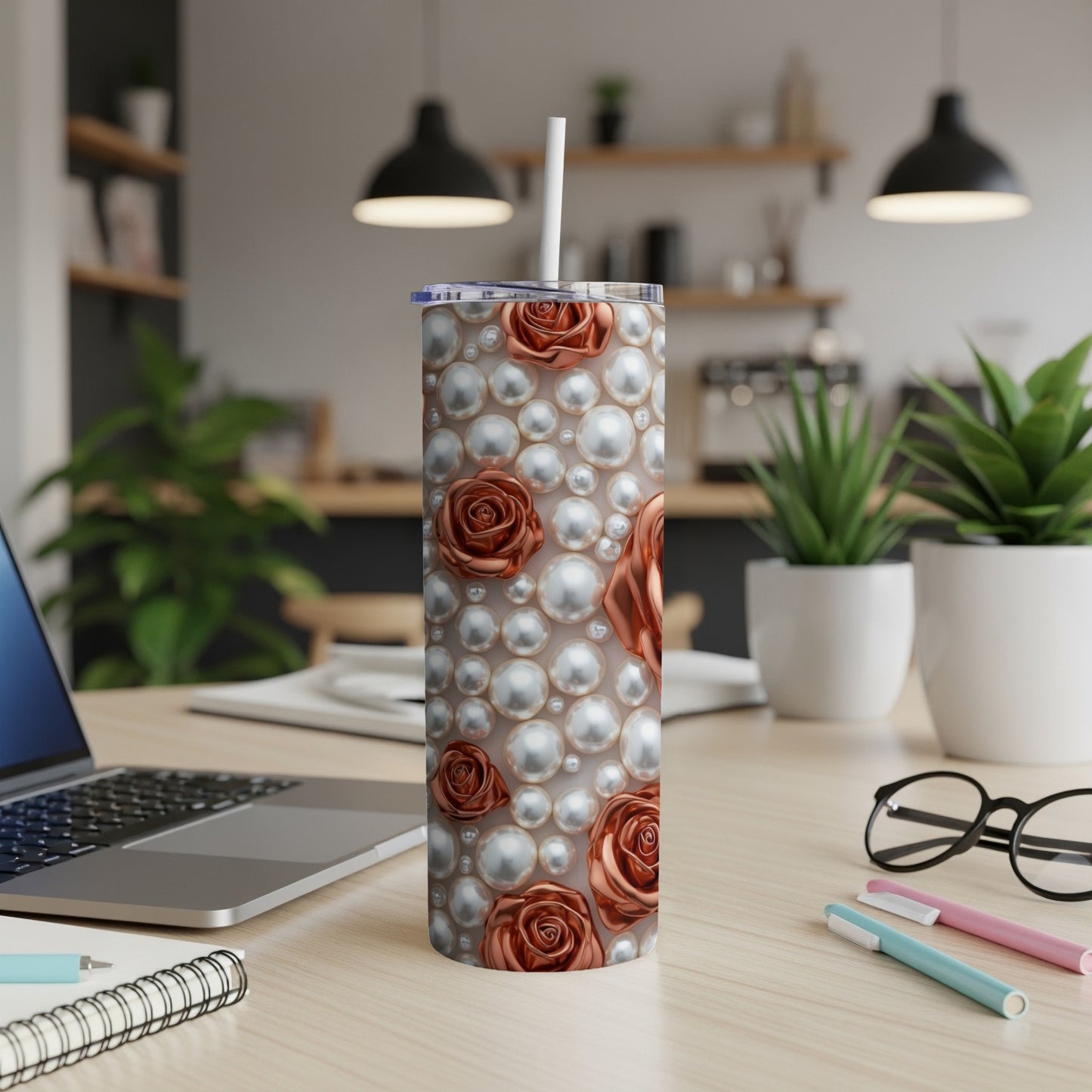 Rose and pearl patterned tumbler with straw on a desk.
