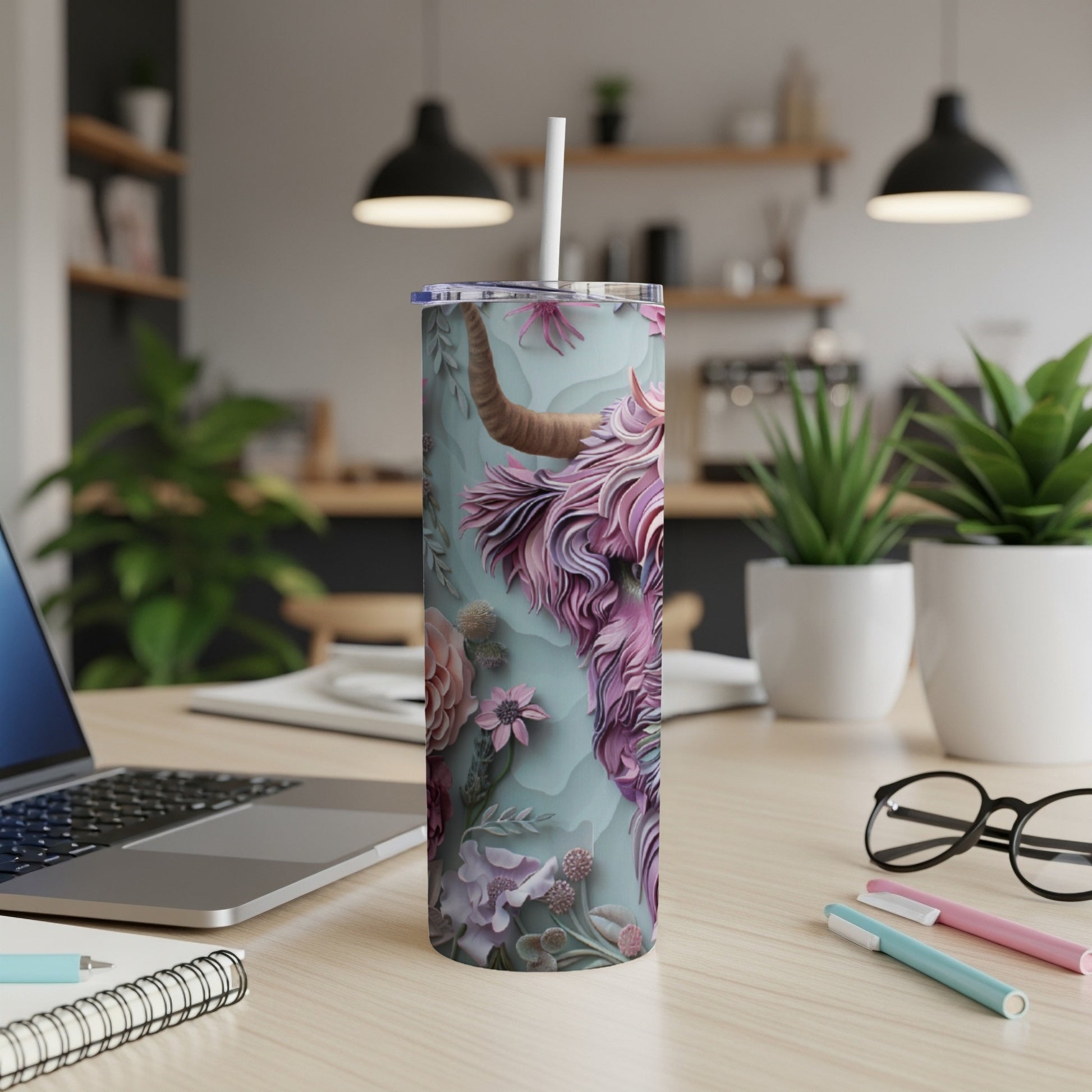 Floral Highland cow tumbler with straw on a desk.