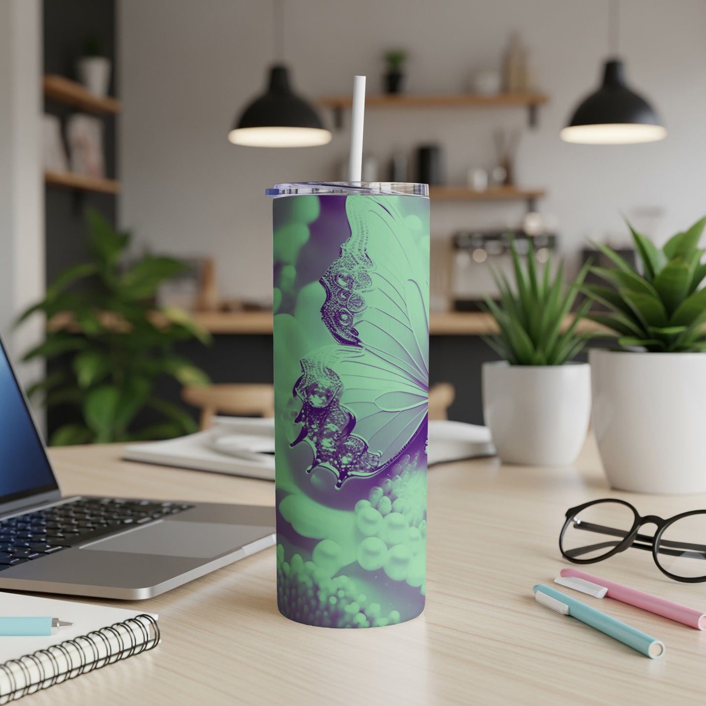 Green and purple butterfly tumbler with straw on a desk.