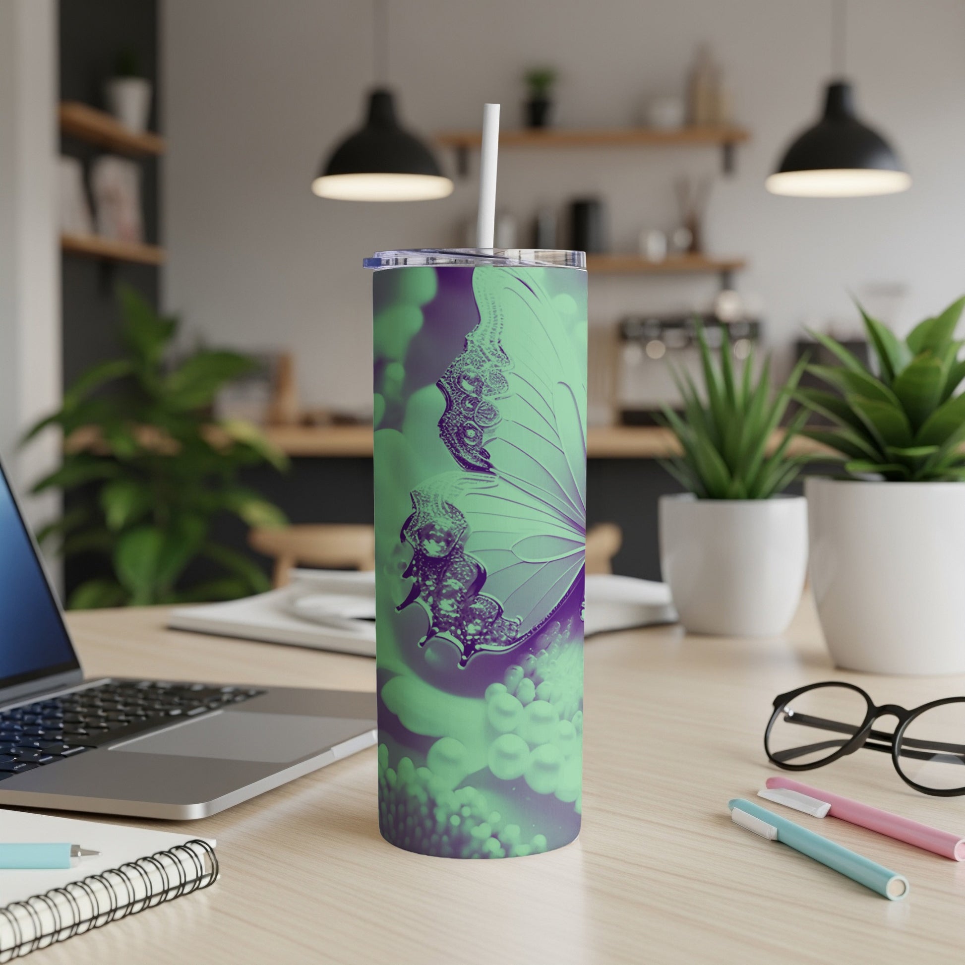 Green and purple butterfly tumbler with straw on a desk.