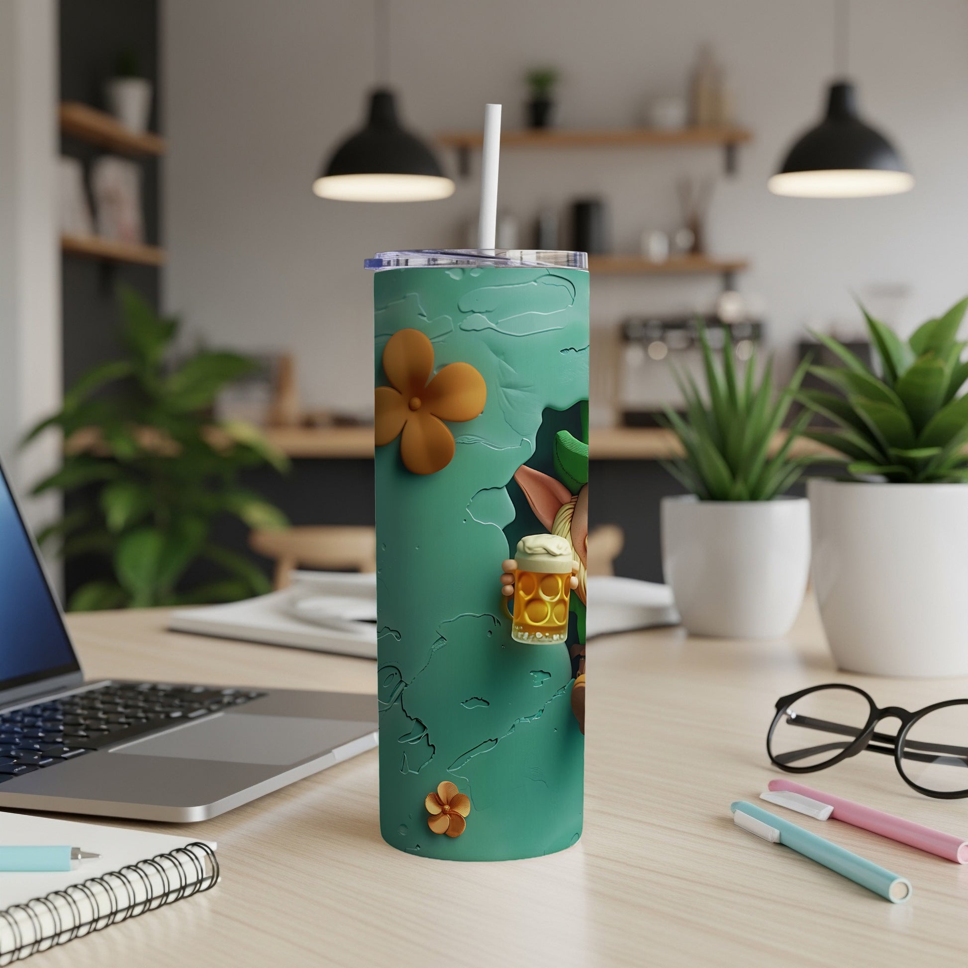Green tumbler with floral and beer mug designs, on a desk.