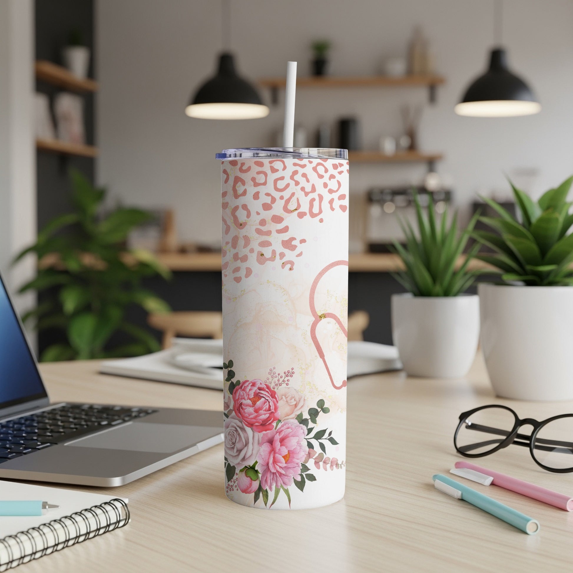 Leopard print and floral patterned insulated tumbler with straw on desk.