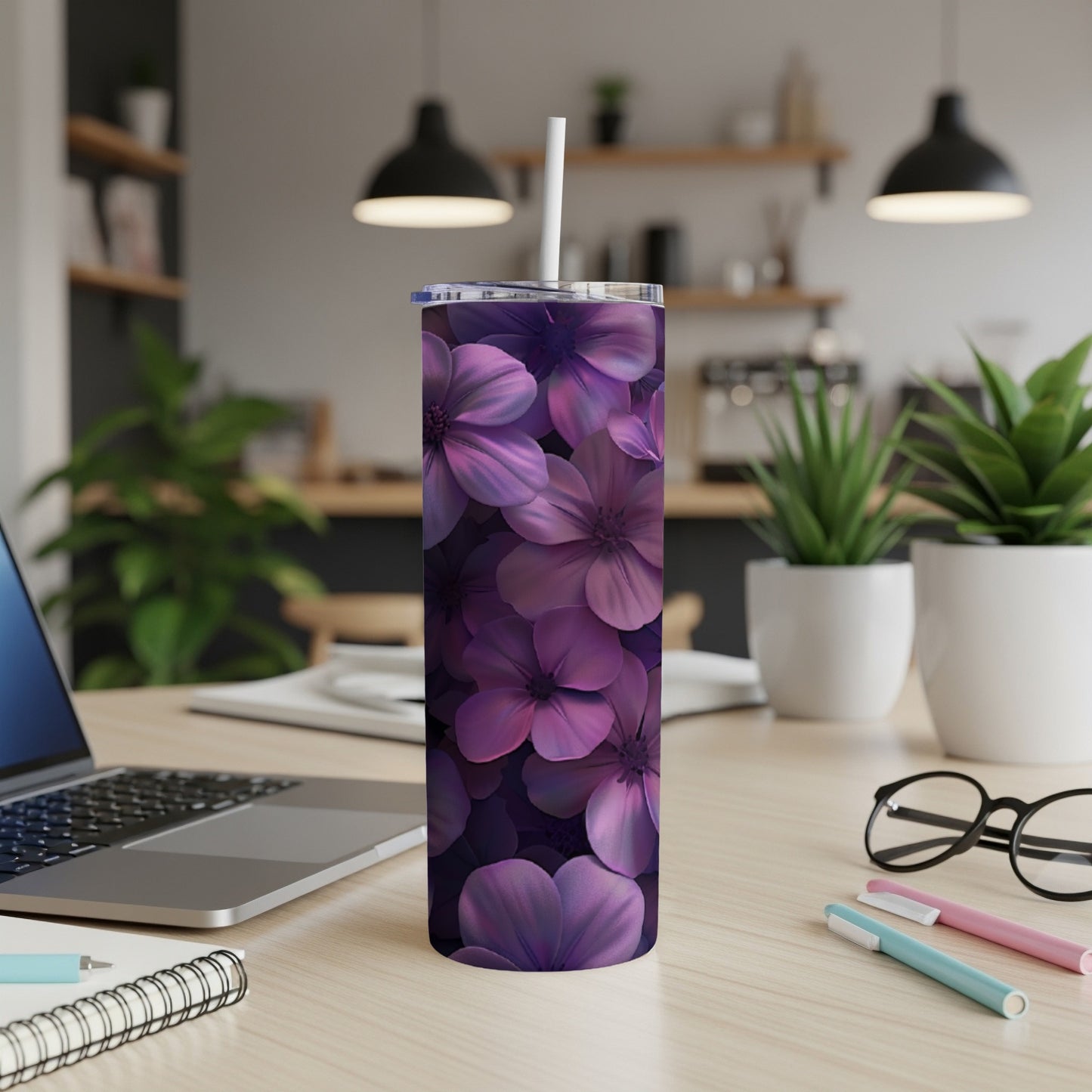 Purple floral tumbler with white straw on desk beside laptop.