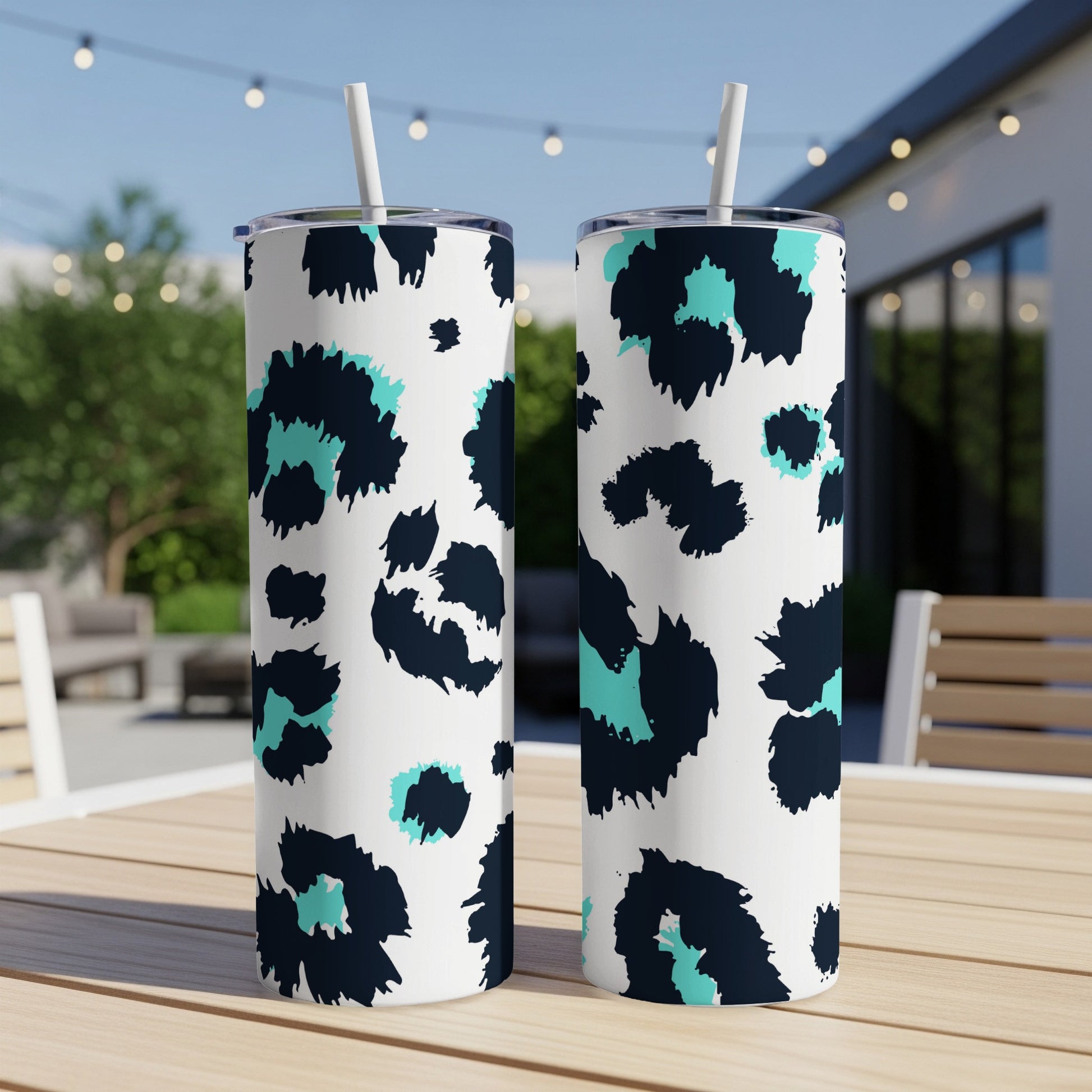Two white tumblers with navy and teal leopard print patterns and straws.