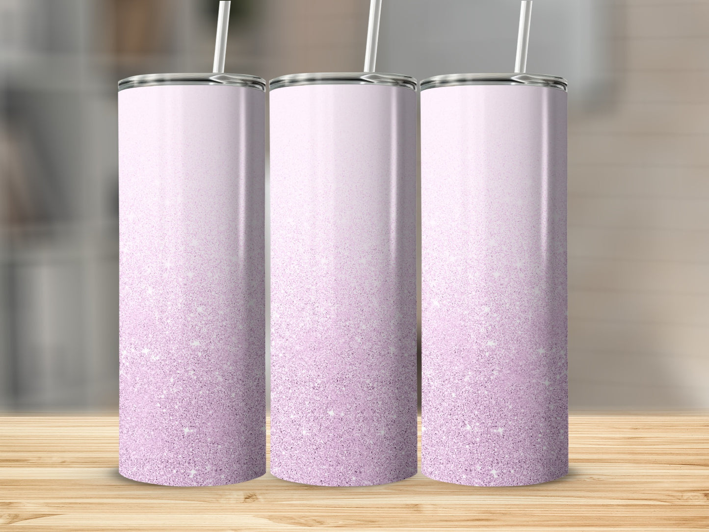 Three tall, iridescent pink tumblers with white straws on a wooden surface.
