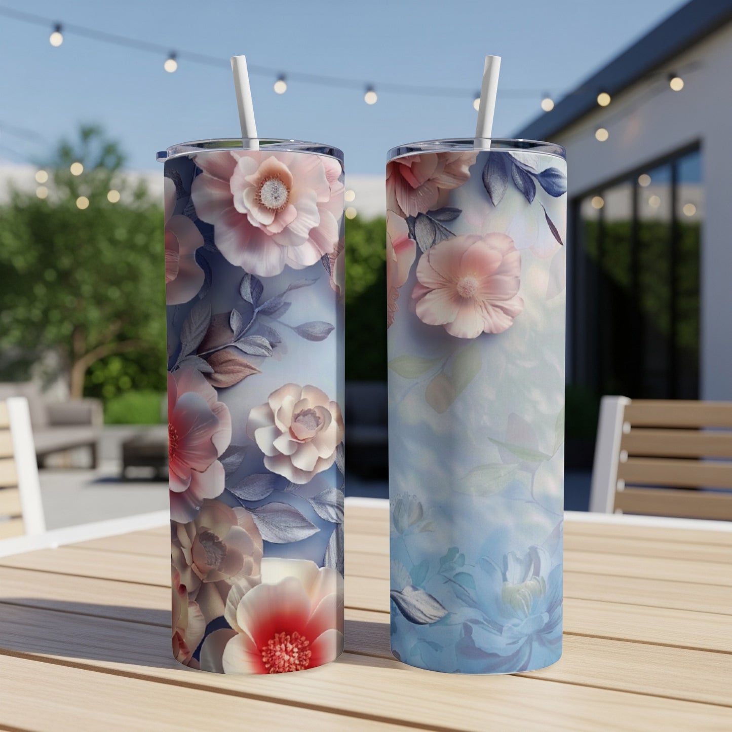 Two floral tumblers with straws on a wooden table.