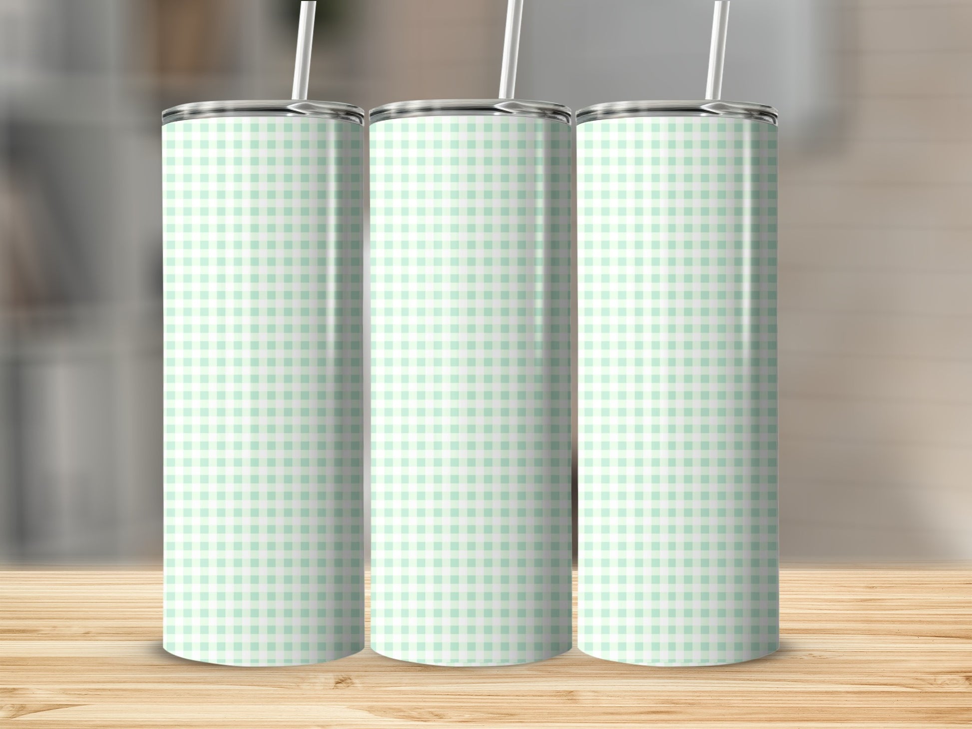 Three mint green and white gingham print tumblers with straws.