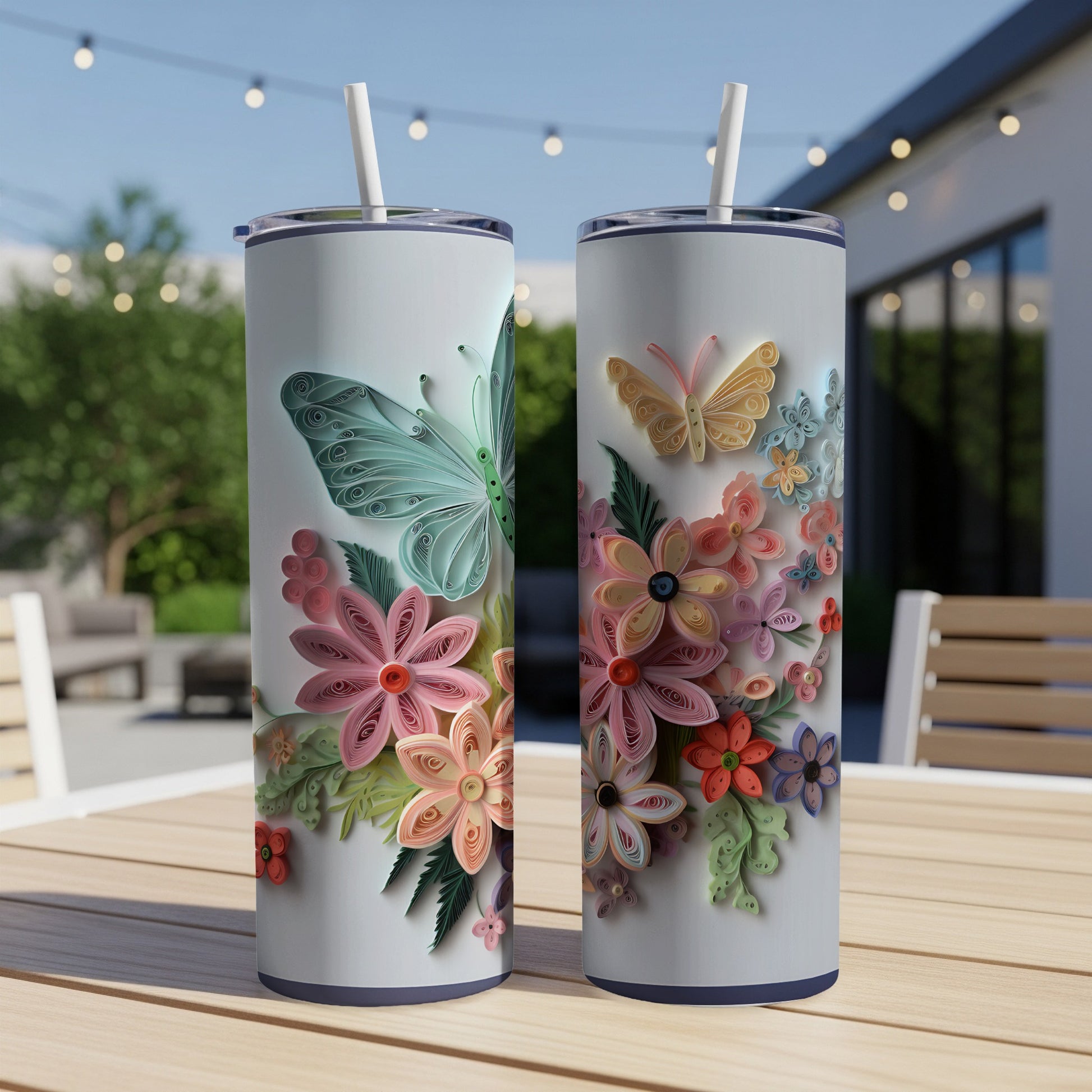 Two white tumblers with quilled butterflies and flowers on a wooden table.