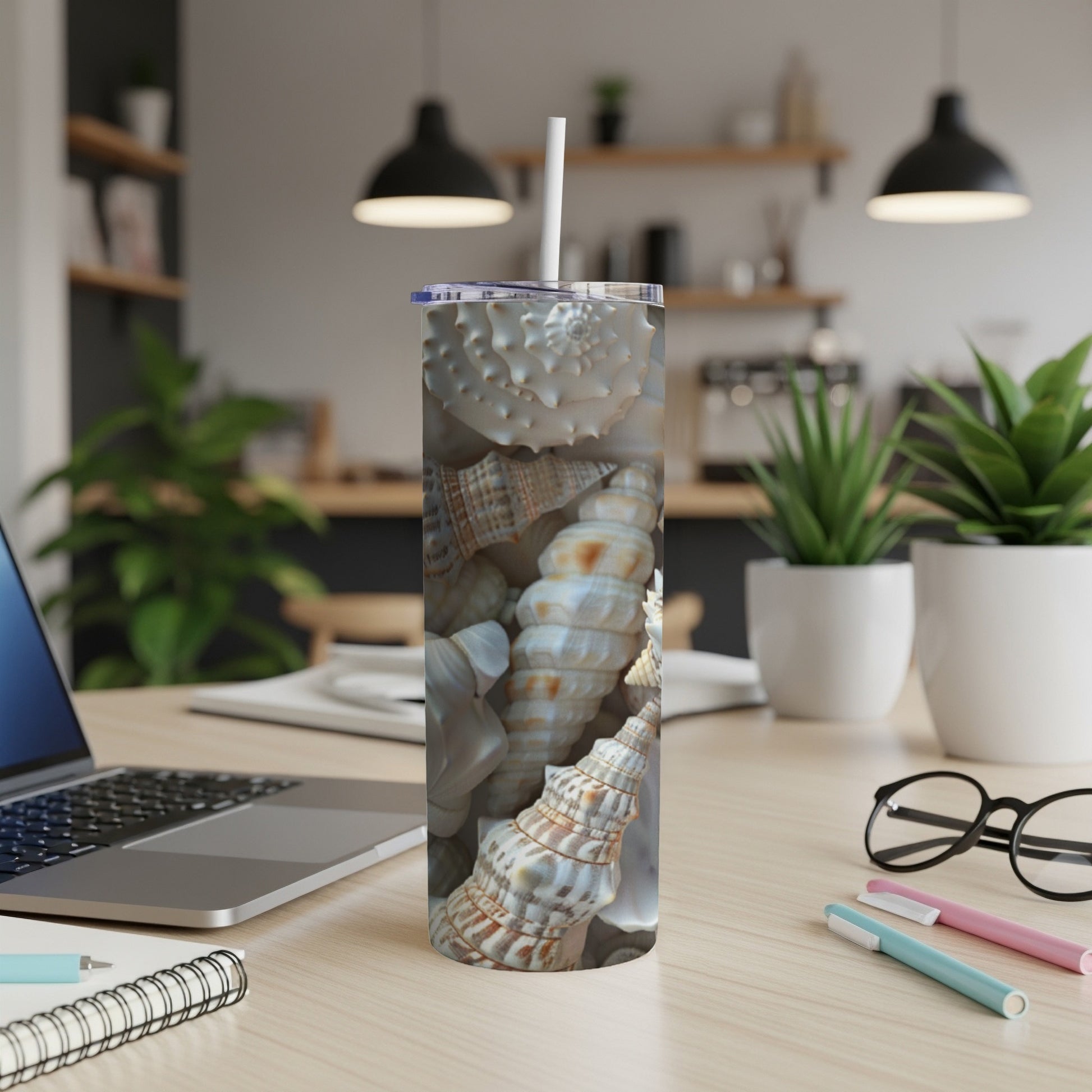 Tall tumbler with detailed seashell pattern on a wooden desk.