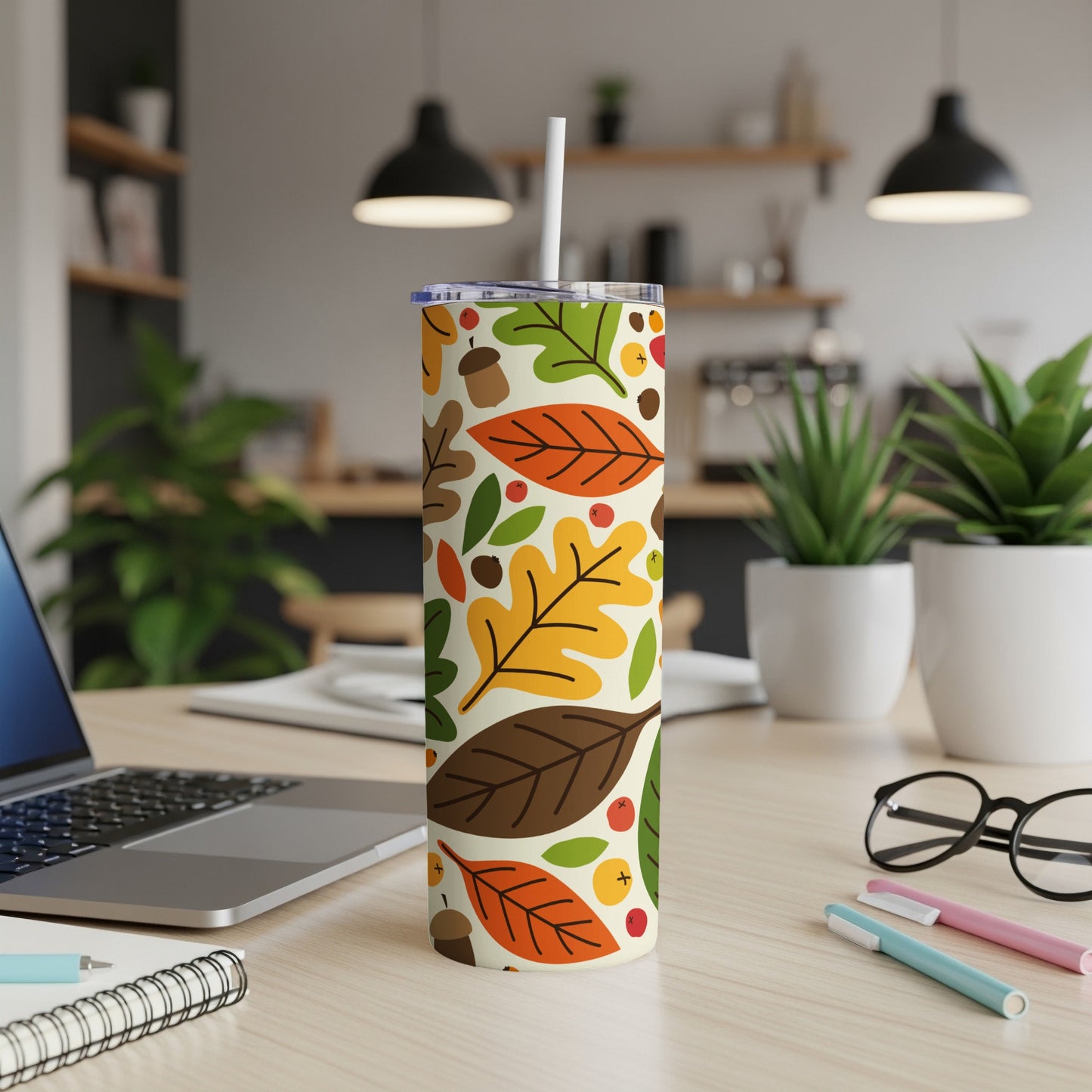 Fall leaves pattern tumbler with straw on a desk.