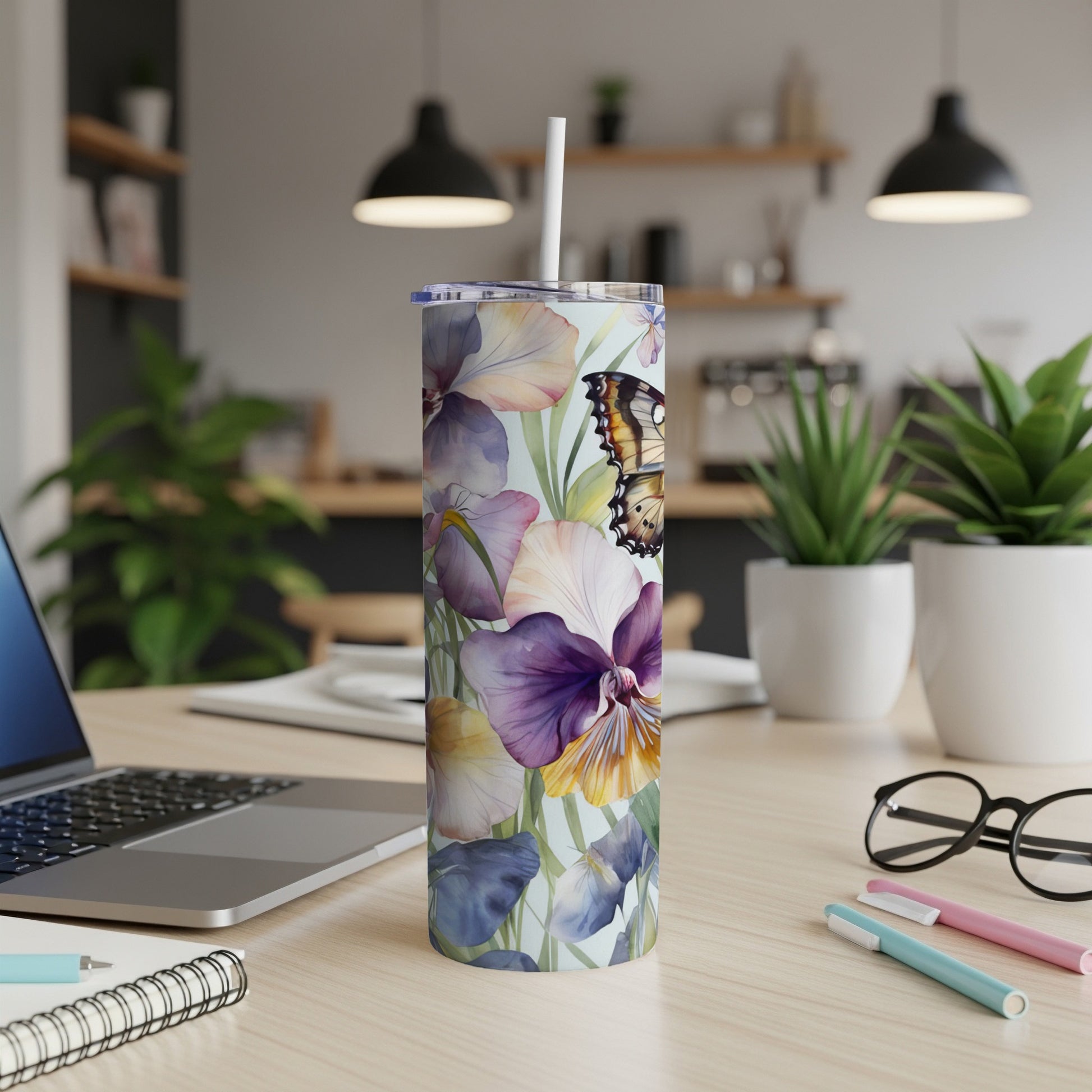 Floral tumbler with butterfly design and straw on a desk.