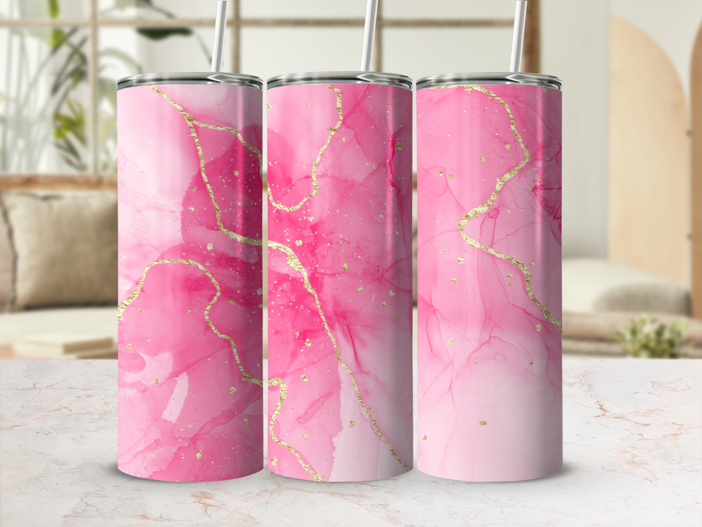Three pink marbled tumblers with gold accents on a countertop.
