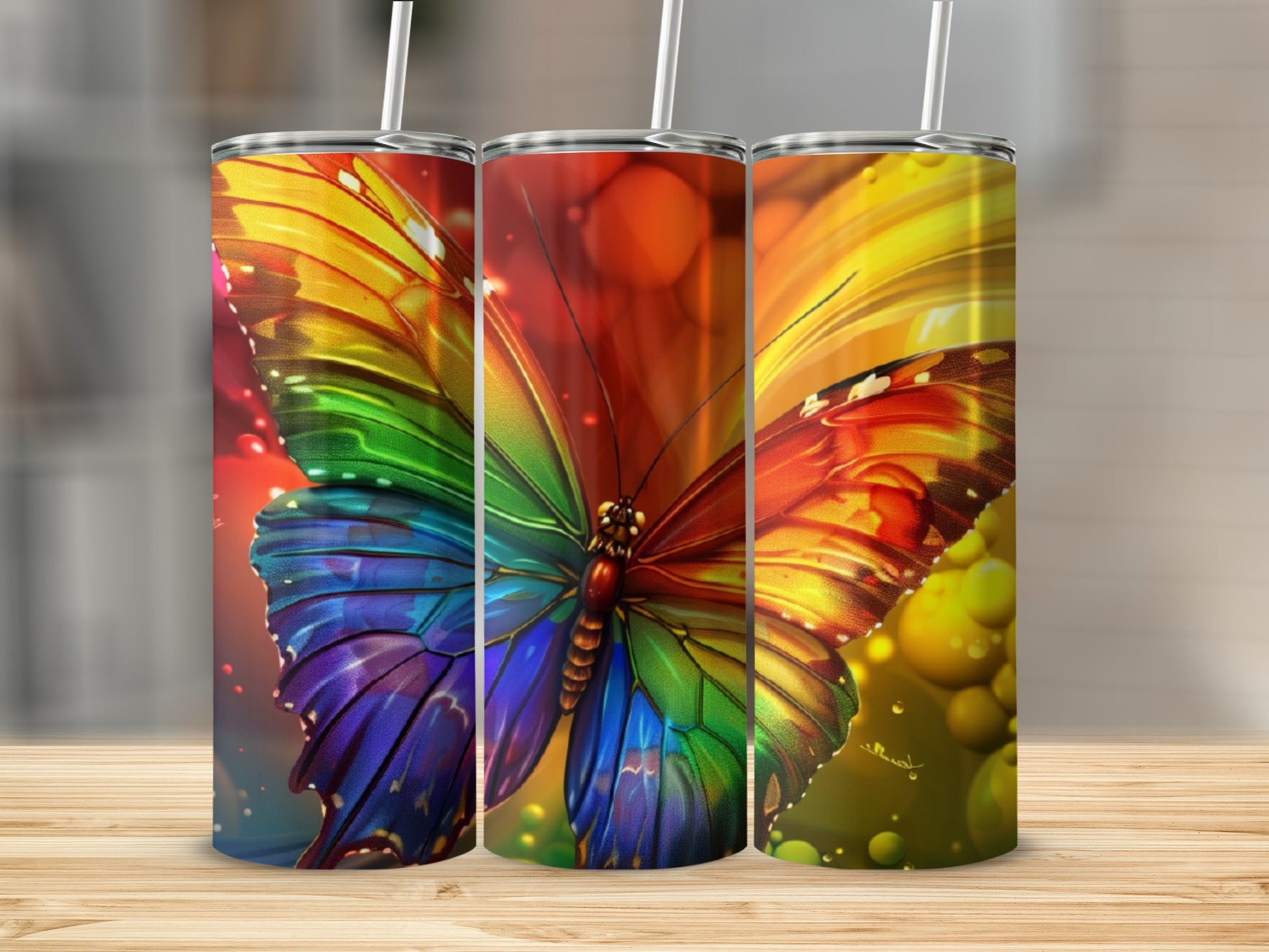 Rainbow butterfly on three tumblers with straw on wooden surface.