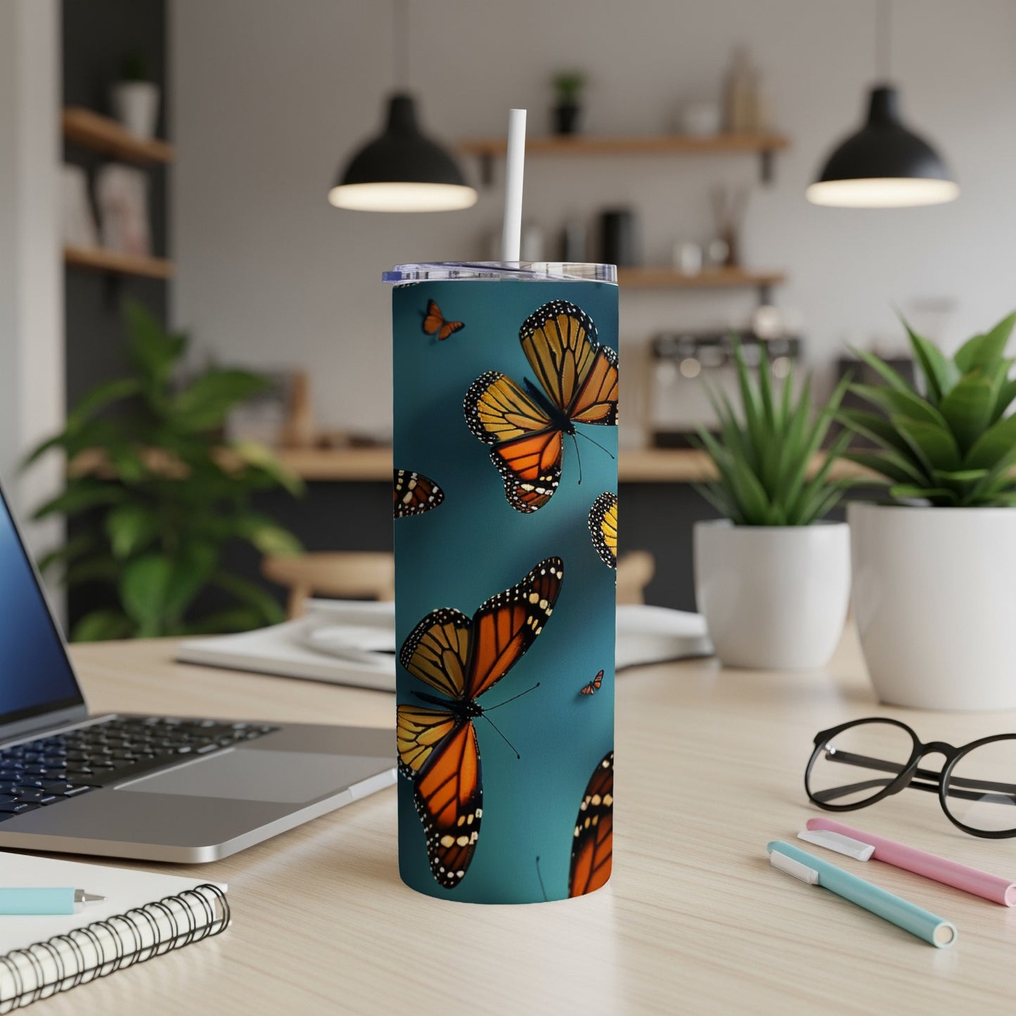 Monarch butterflies flutter on a teal background of a white tumbler.
