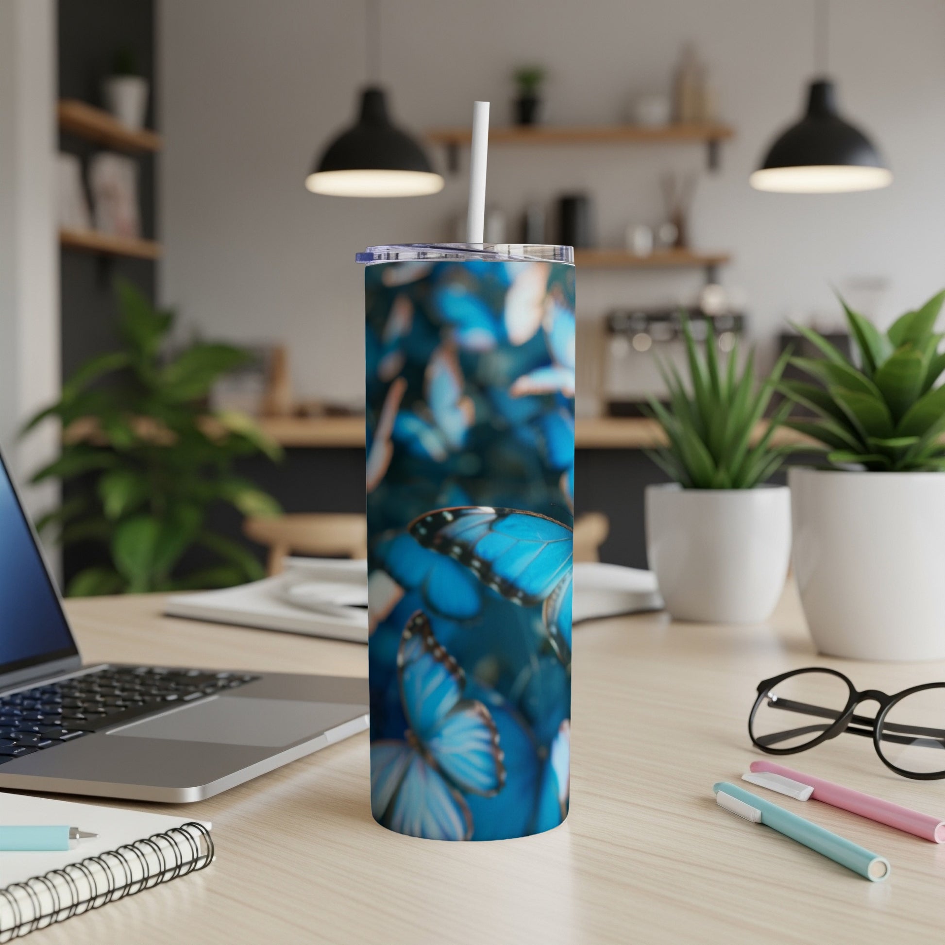 Blue morpho butterflies on a blue patterned skinny tumbler with a white straw.