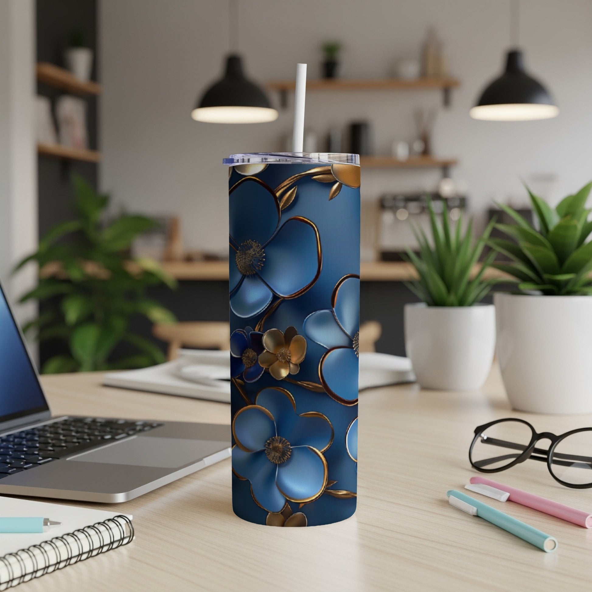 Blue tumbler with gold floral accents on a desk with a laptop.