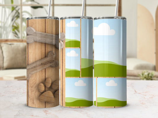 Three tumblers: one with wood grain, bone, and paw print; two with cloud and hill designs.