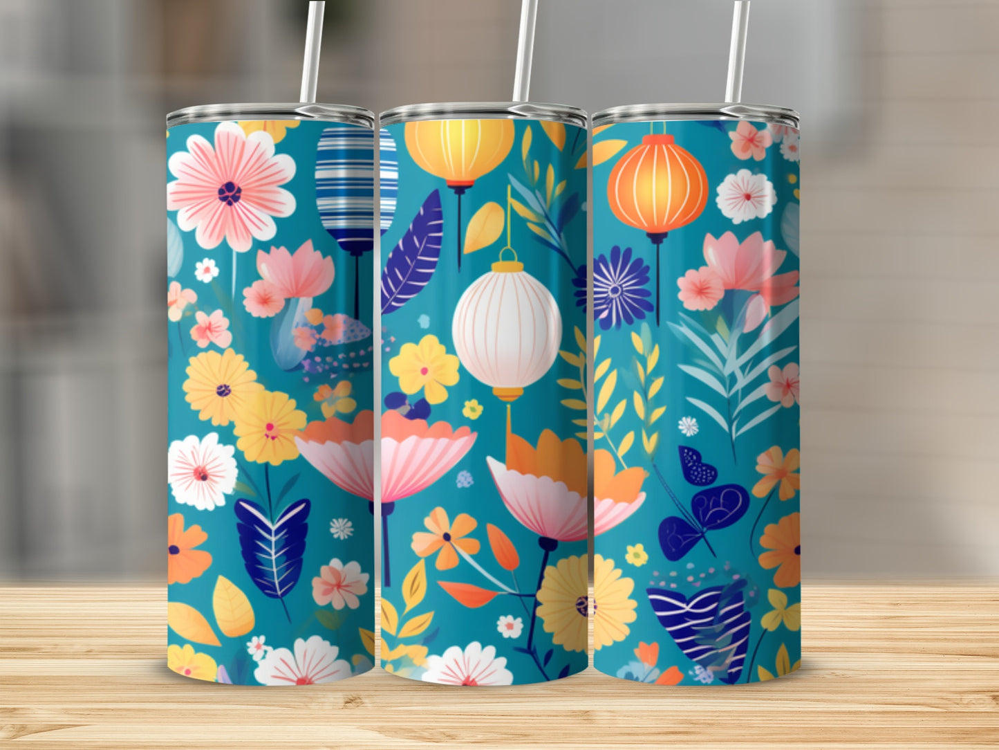 Three teal tumblers with floral and lantern patterns on a wooden surface.