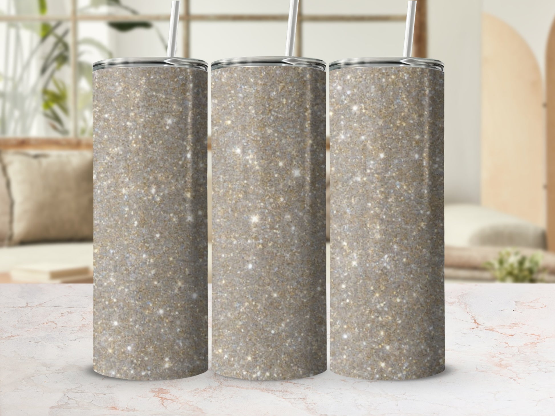 Three sparkly glitter tumblers with straws on a marble countertop.