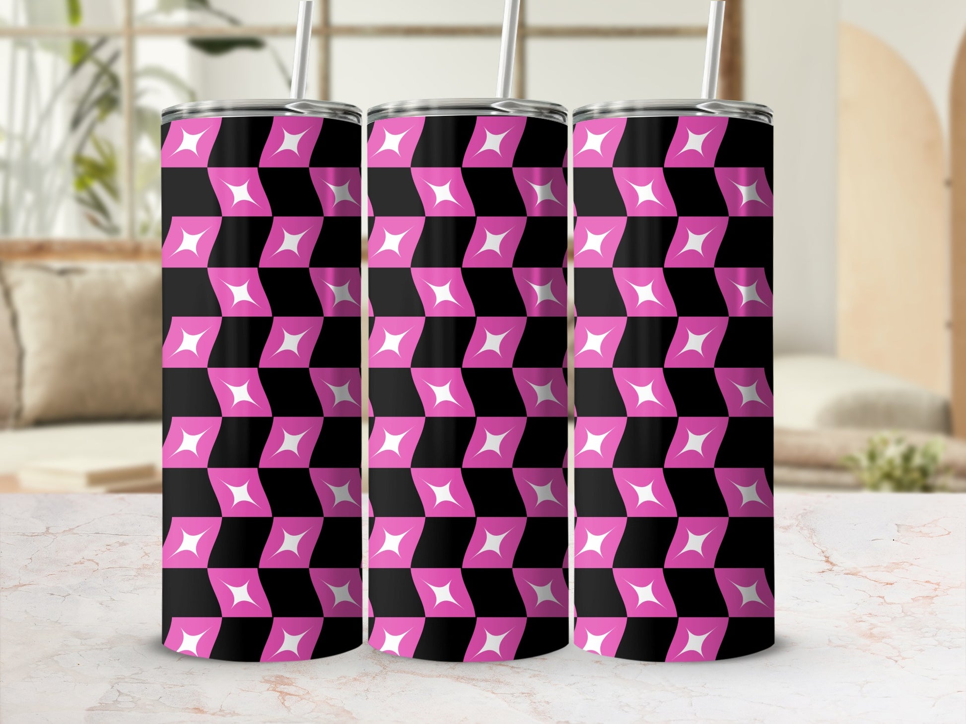 Three pink and white geometric pattern tumblers with straws on a marble surface.