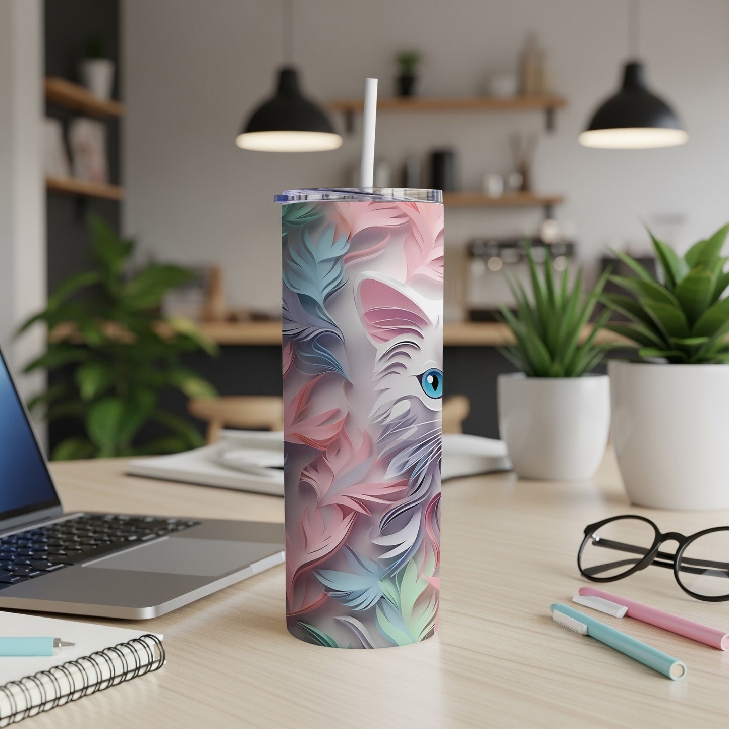 White cat face design on a pink and blue feather patterned skinny tumbler.