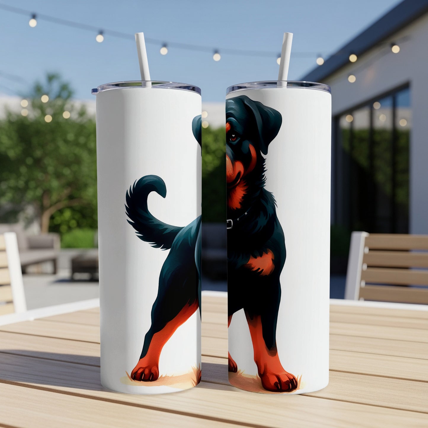 Two Rottweiler dog tumblers with straws on a wooden table outdoors.