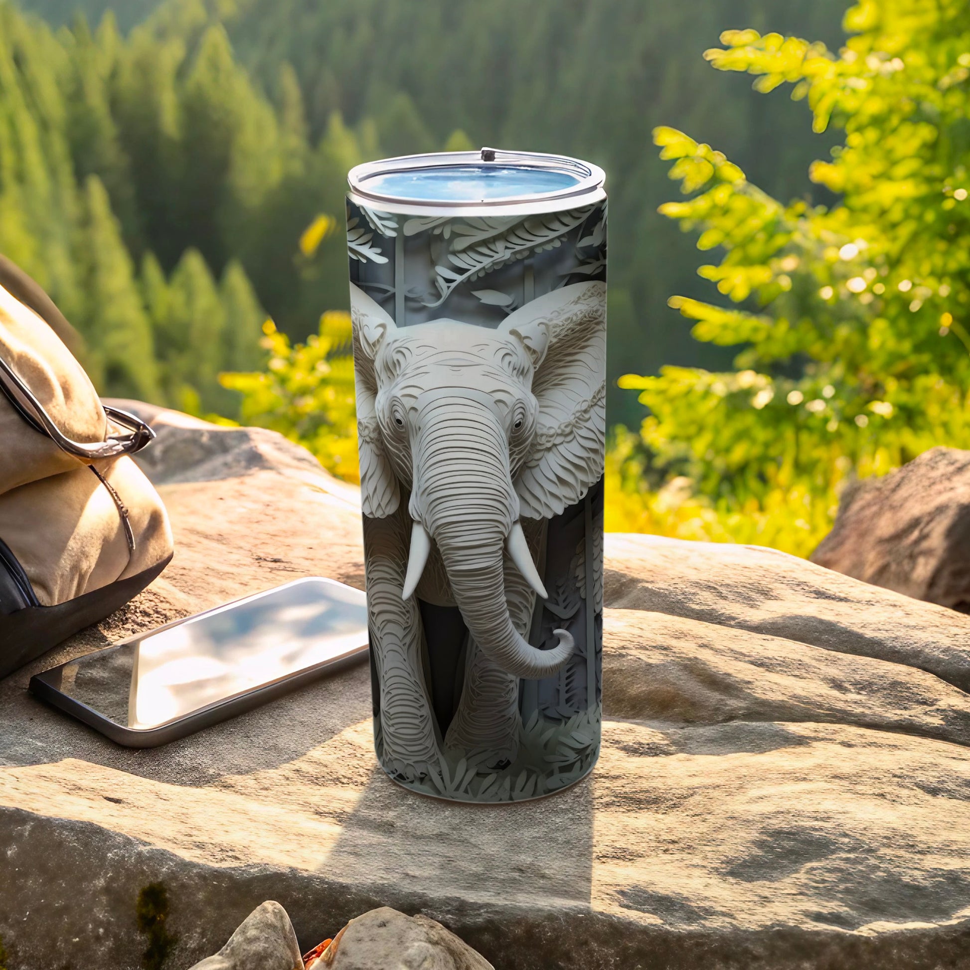 Gray tumbler with embossed elephant head design, resting on rocks.