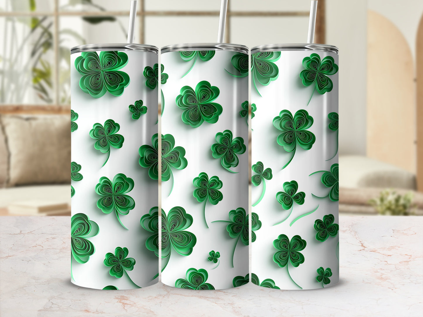 Three green clover pattern tumblers with straws on a marble surface.
