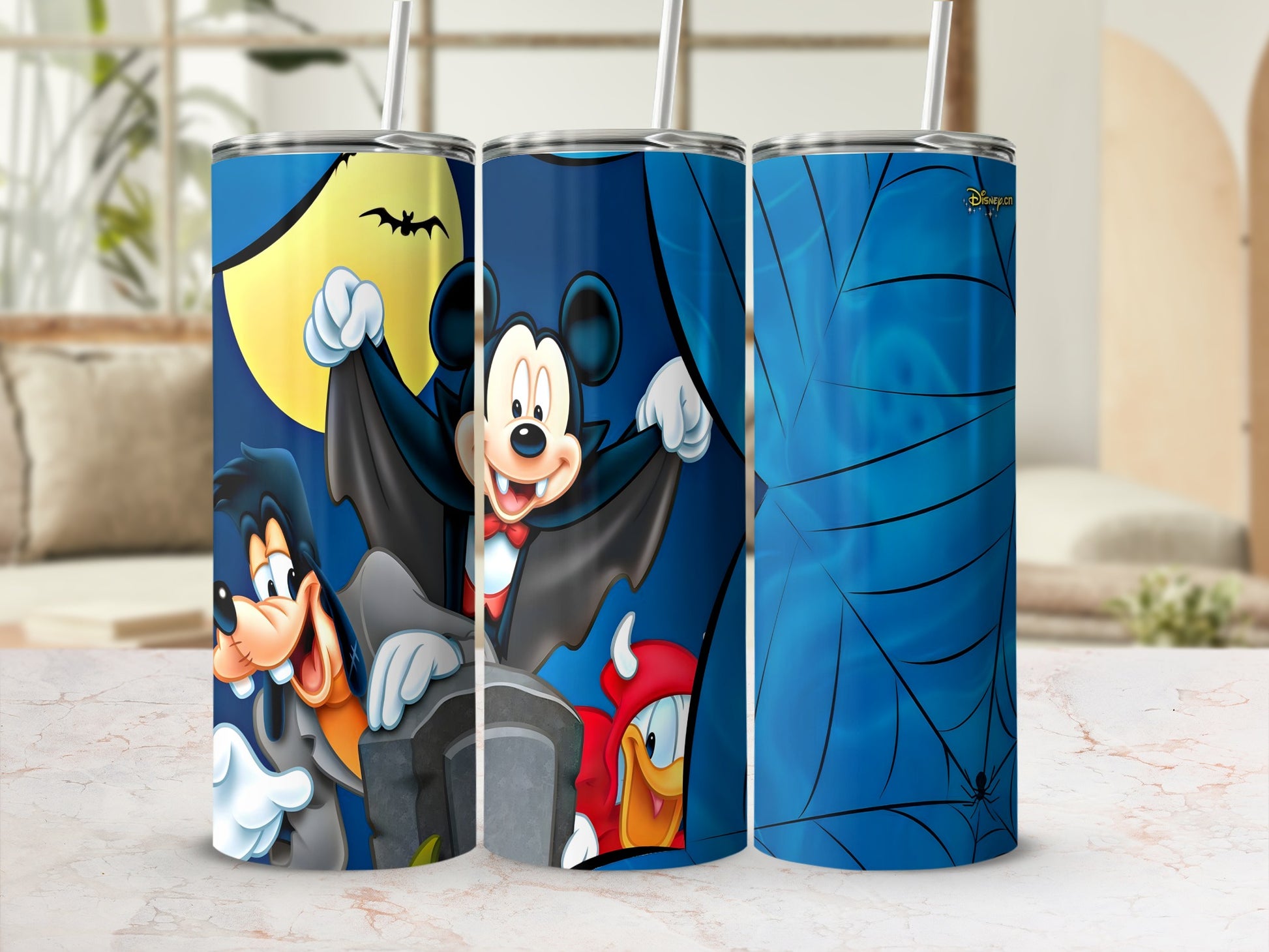 Mickey Mouse, Goofy, and Donald Duck in Halloween costumes on tumblers.