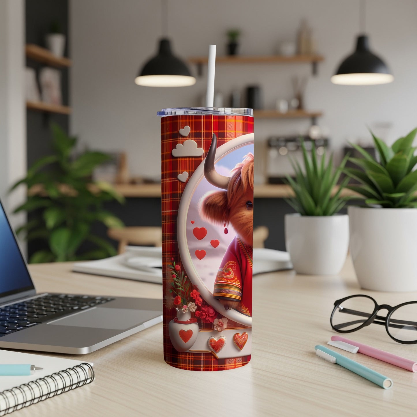 Red plaid tumbler with highland cow and hearts, on a desk.
