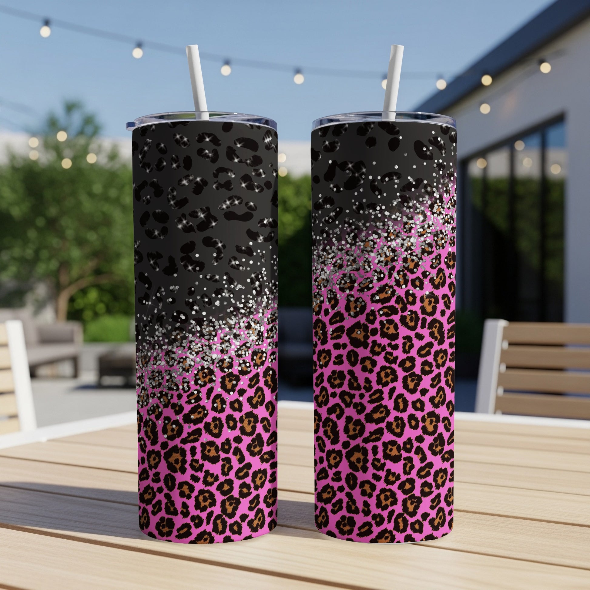 Two tumblers with leopard print and glitter designs sit on a table.