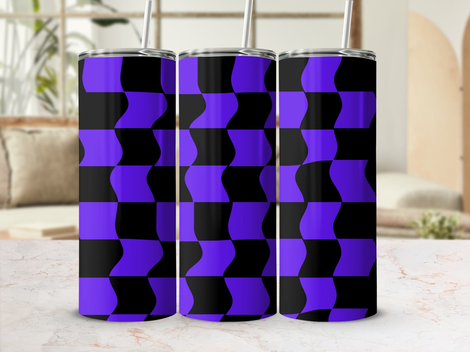 Three purple and black checkered tumblers with straws on a counter.